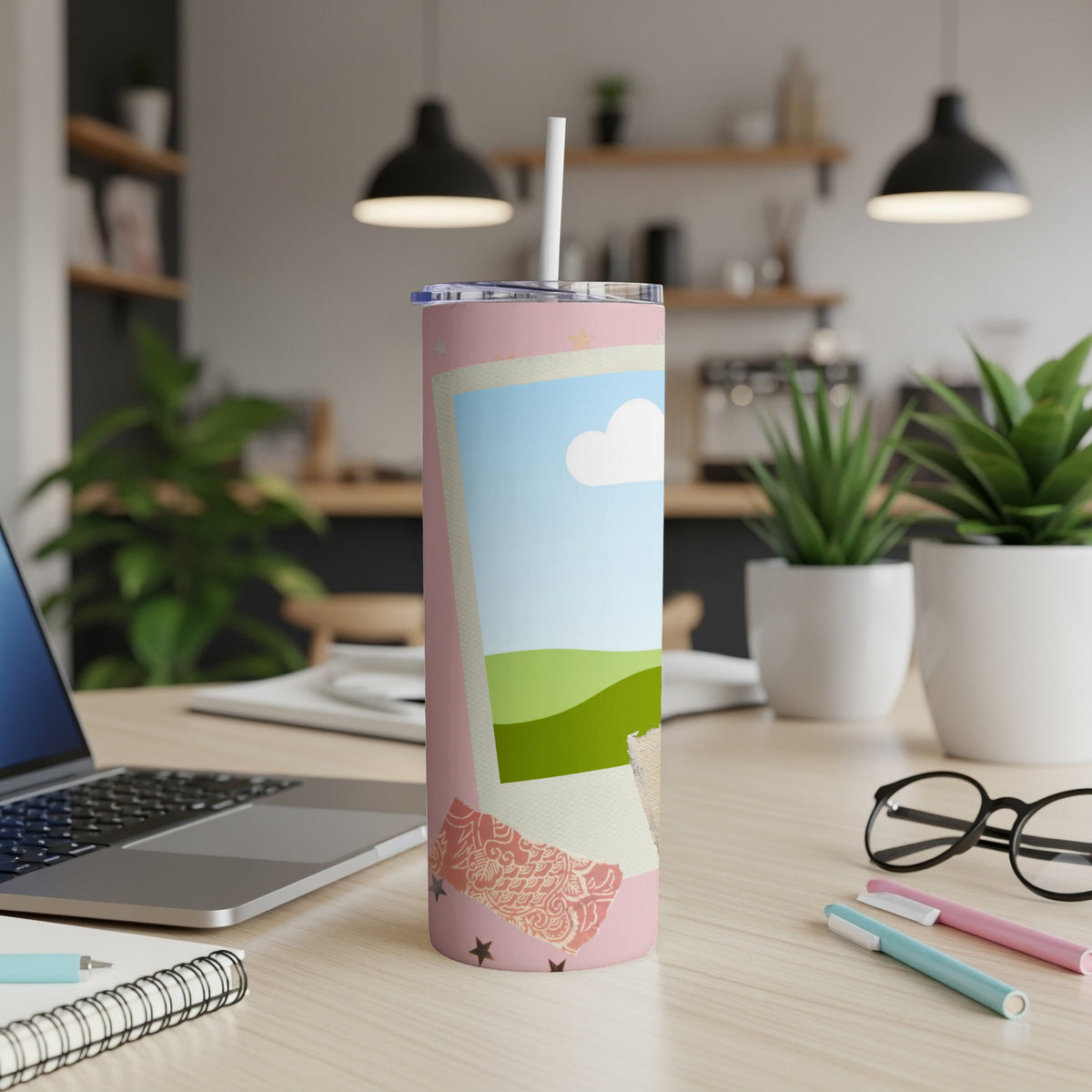 Pink tumbler with landscape photo design and straw on a desk.