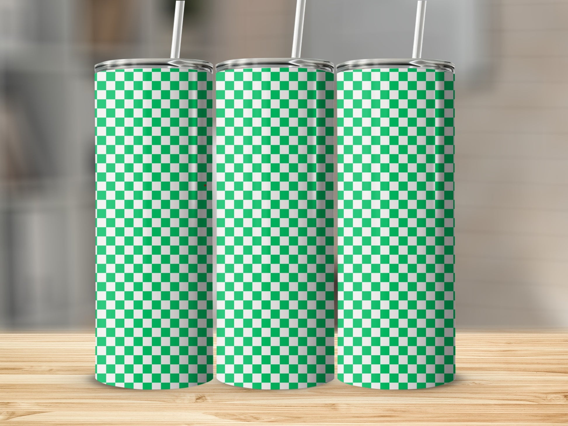 Three green and white checkered tumblers with straws on a wooden surface.
