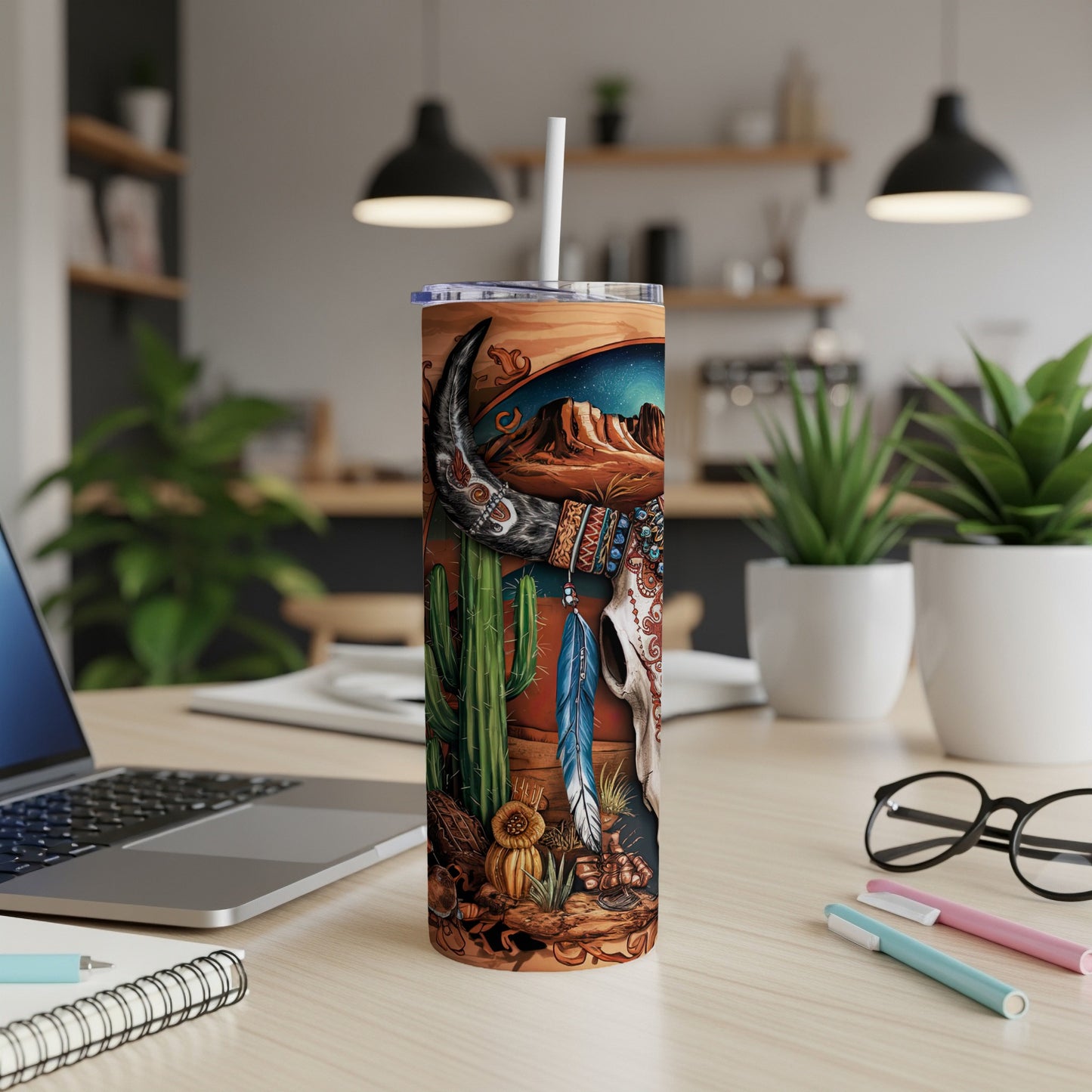 Desert scene with bull skull, cacti, and feathers on a tumbler.