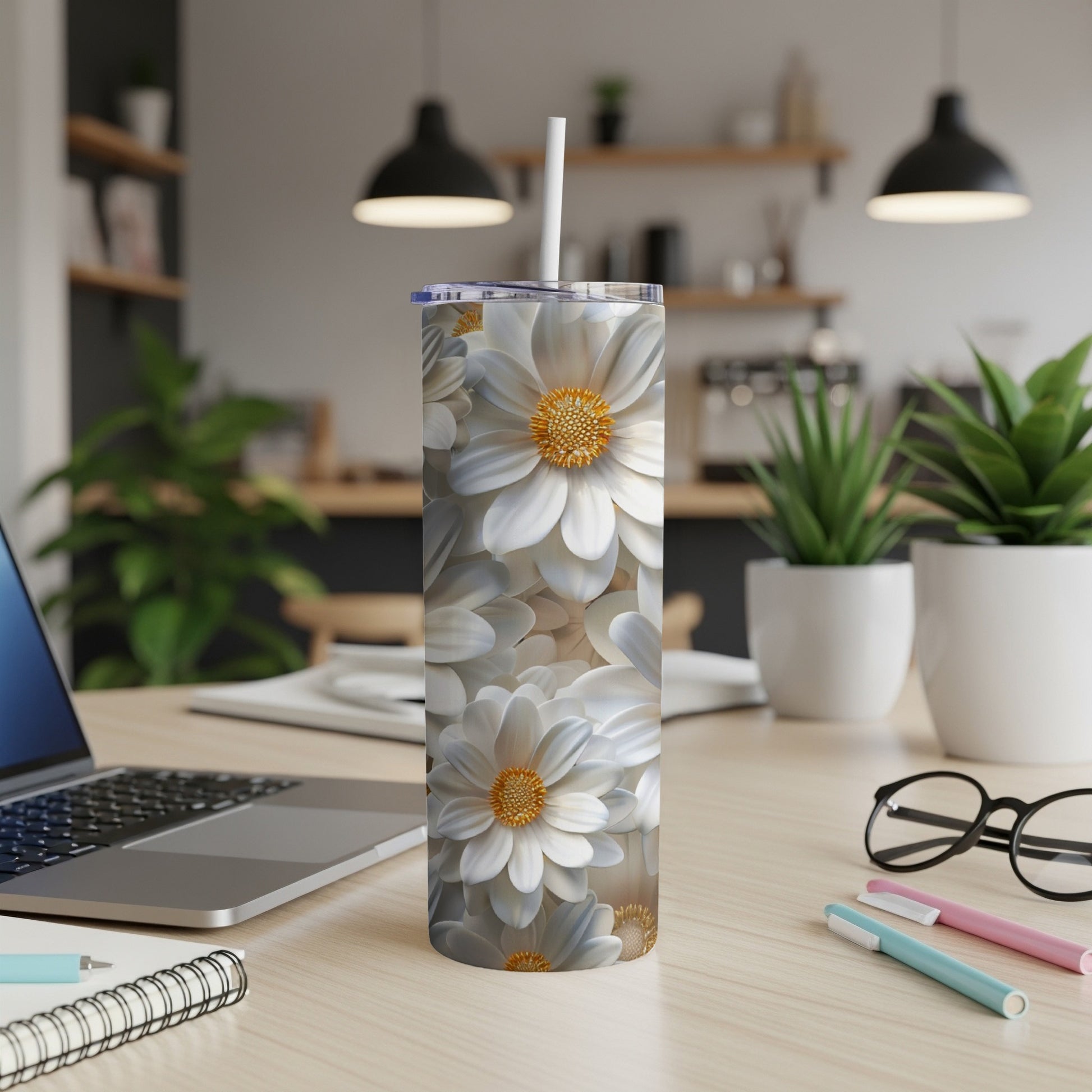 White floral patterned tumbler with straw on a wooden desk.