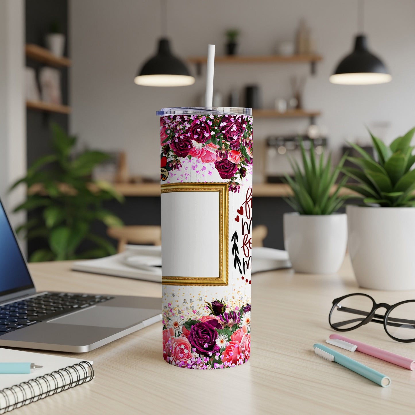 Floral patterned tumbler with a gold frame and straw on a desk.