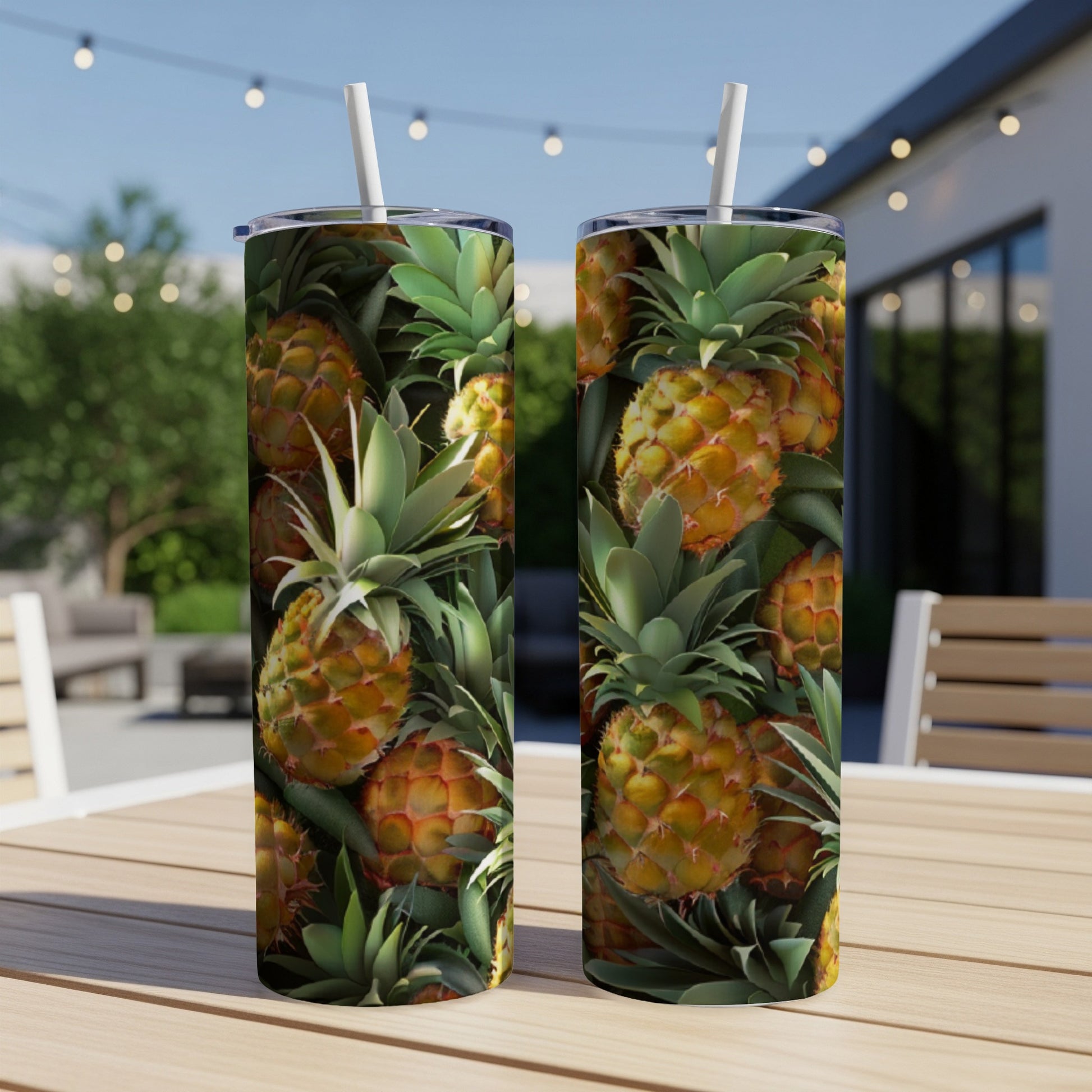 Two tumblers with a repeating pineapple pattern on a wooden table outdoors.