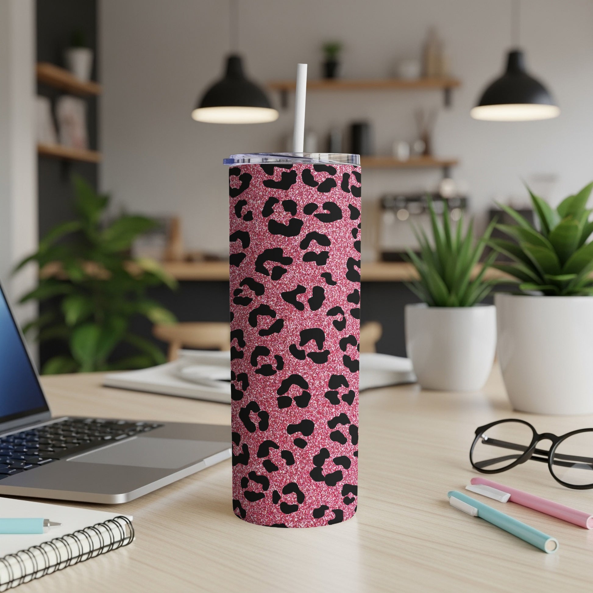 Pink glitter tumbler with black leopard print and straw on a desk.