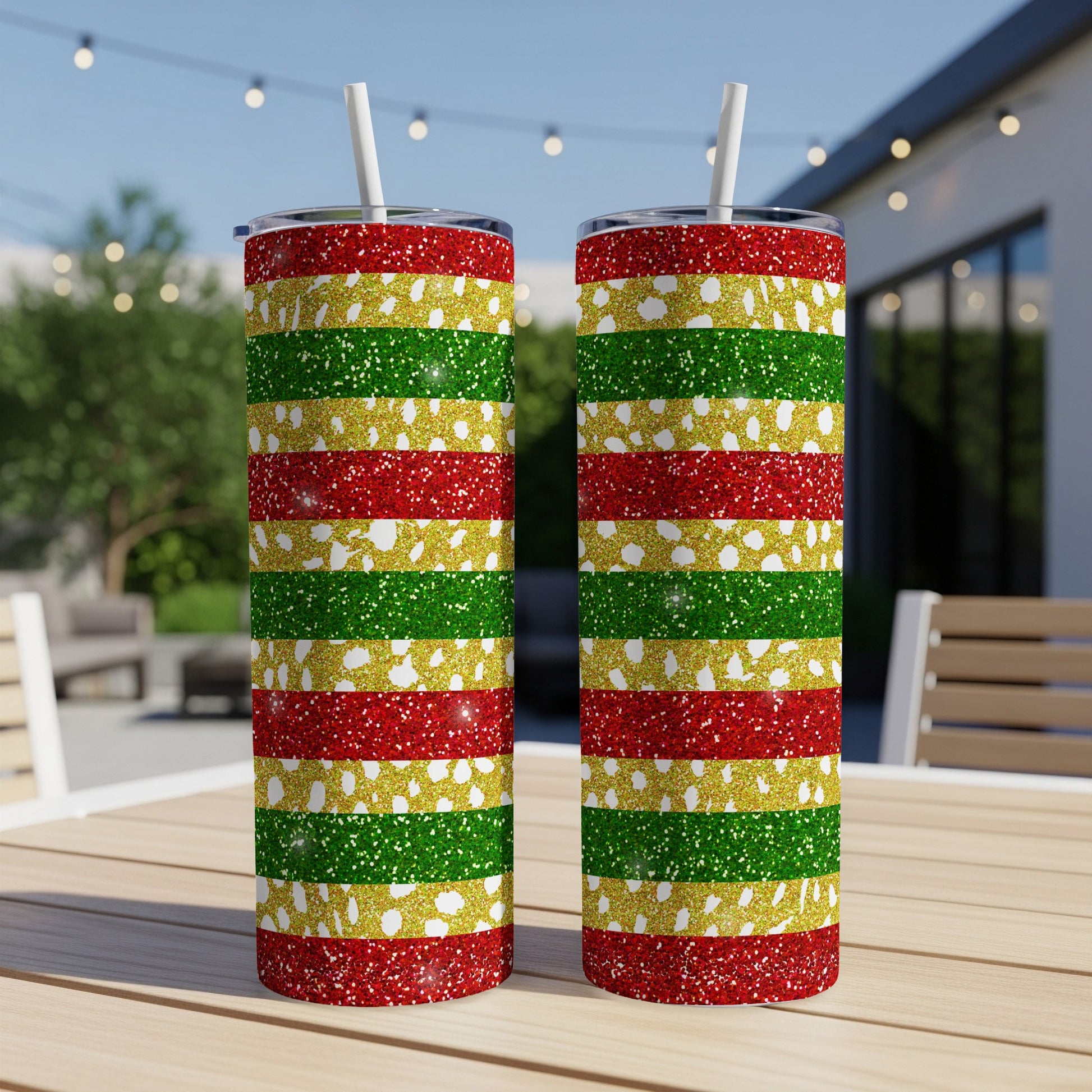Two glittery tumblers with red, green, and gold stripes on a wooden table.