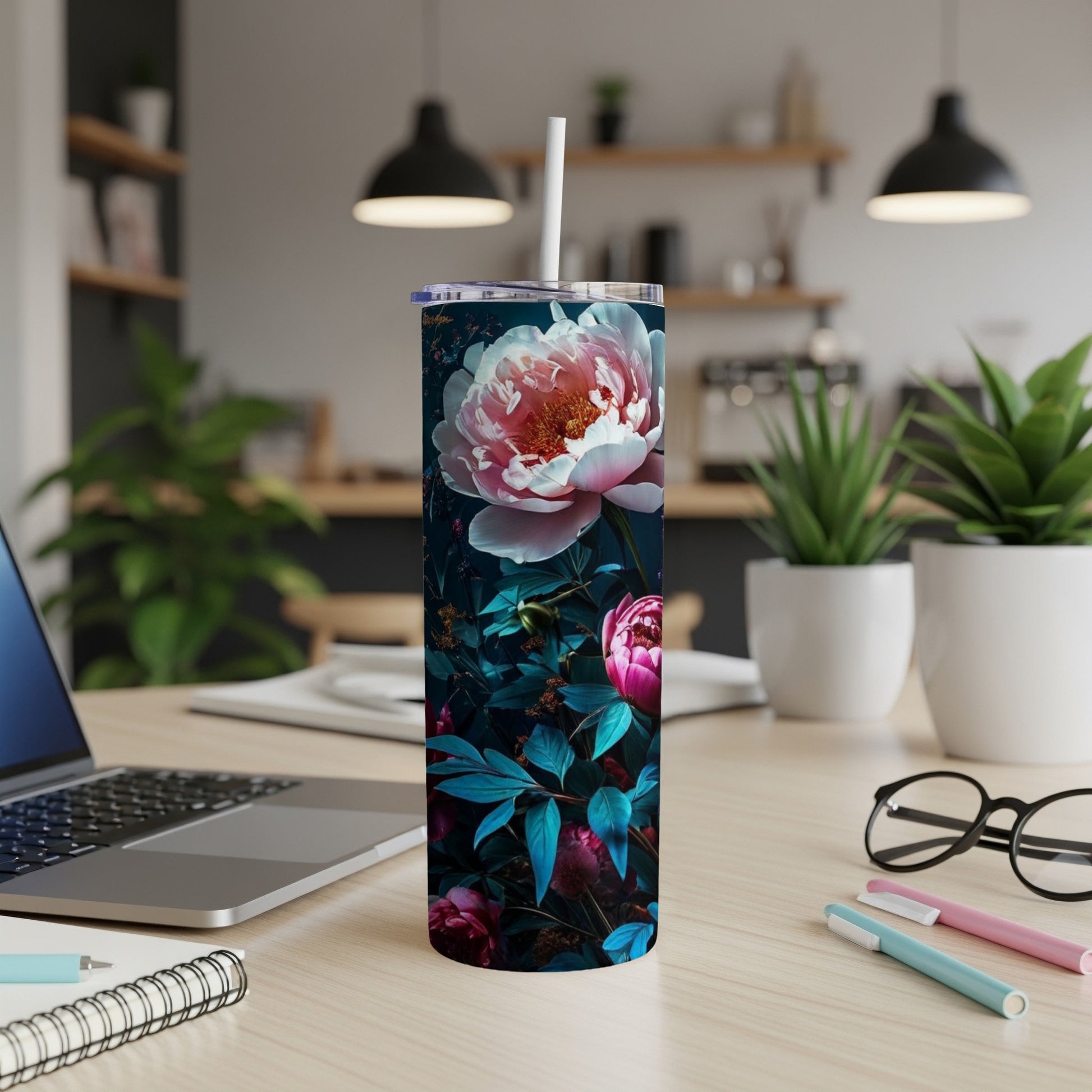 Floral skinny tumbler with pink peony and dark leaves on desk.