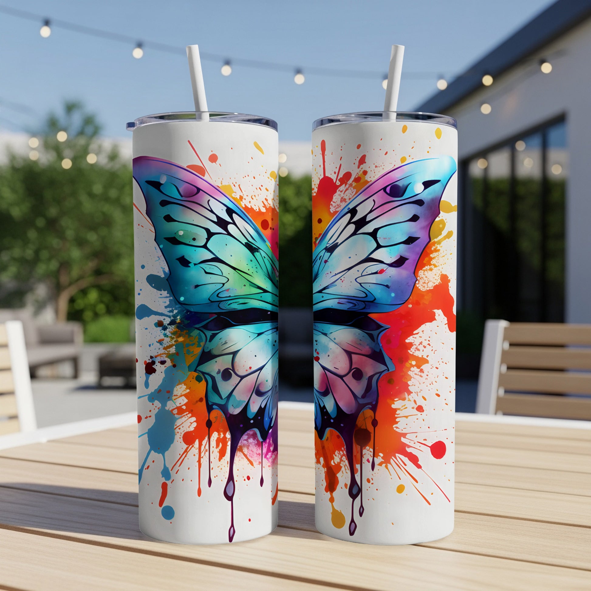 Two white tumblers with colorful butterfly wing designs and vibrant paint splatters.