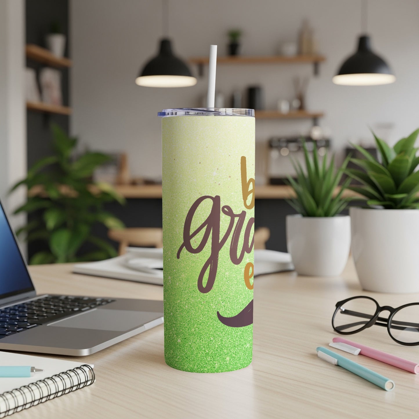 Green glitter tumbler with "be grateful" text on a desk.
