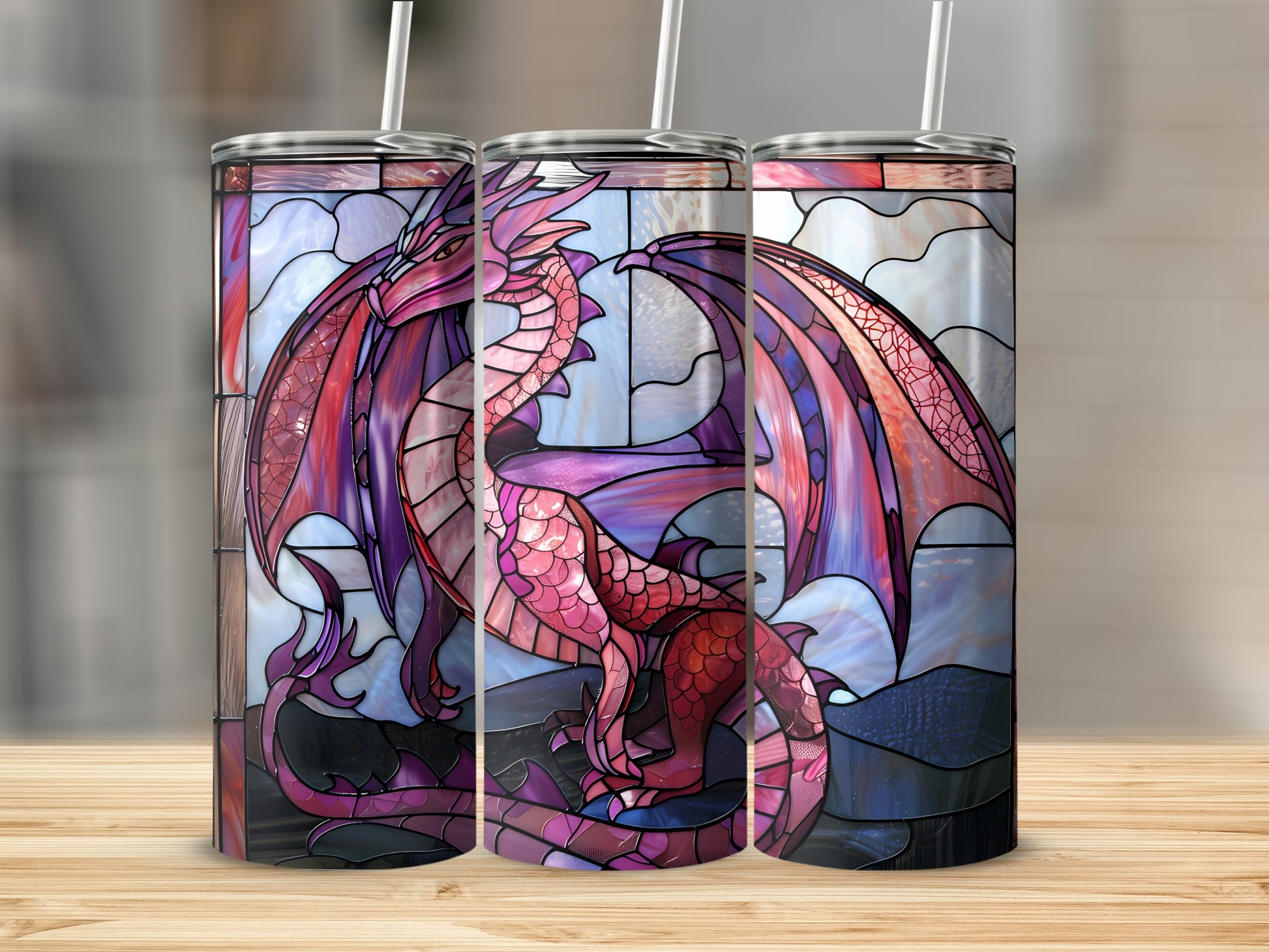 Dragon stained glass design on three tumblers on a wooden surface.