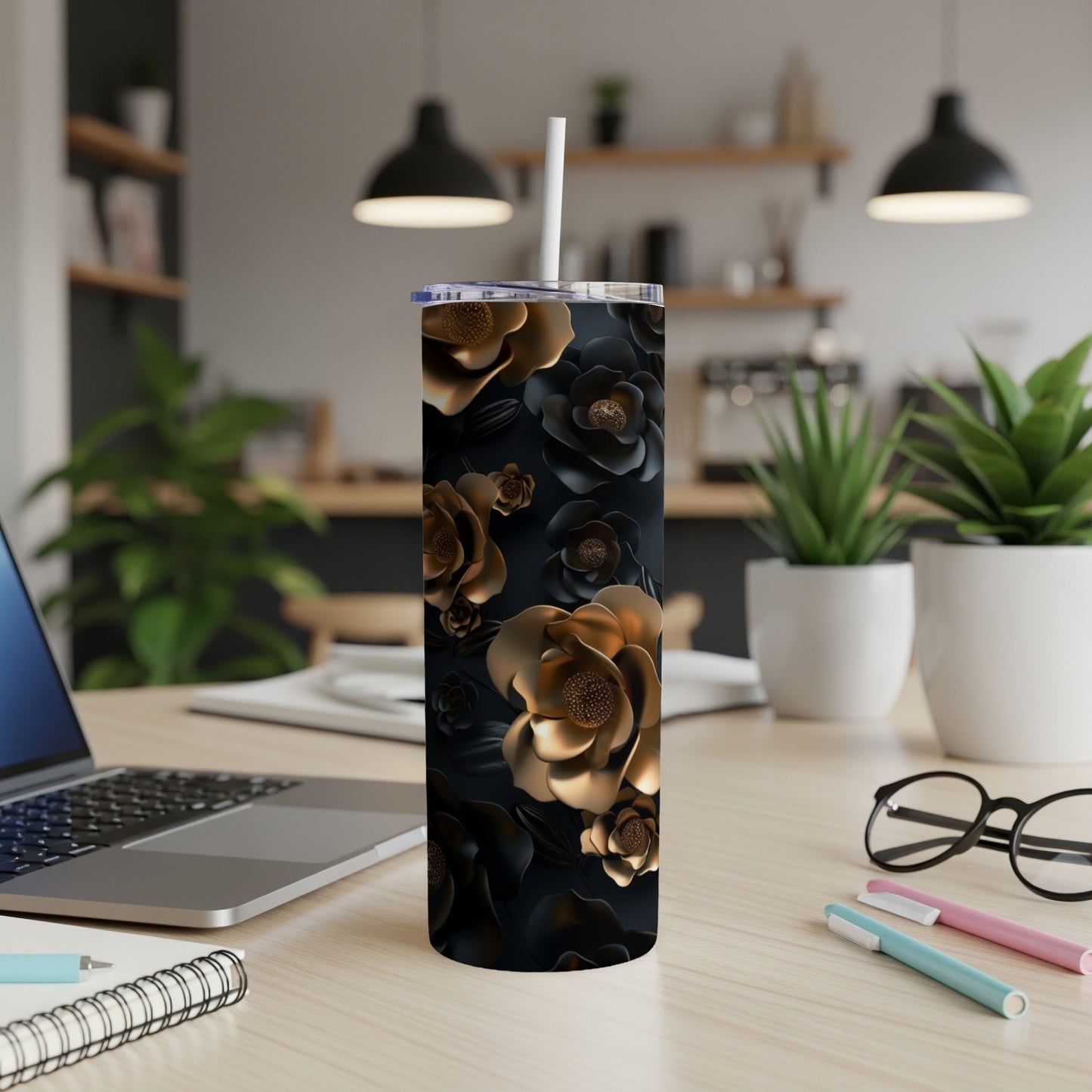Black tumbler with gold floral pattern and straw on desk.