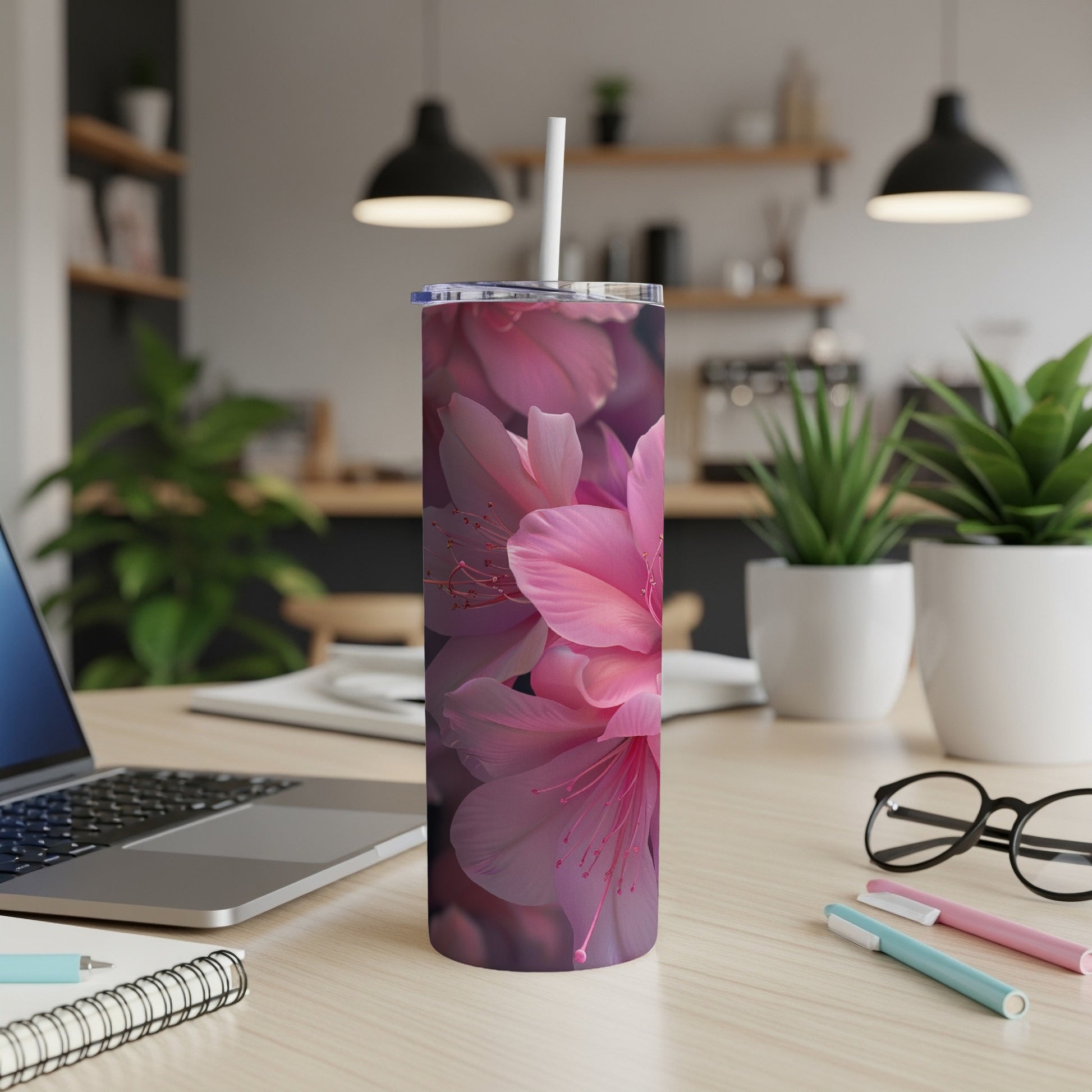 Pink floral design on a white tumbler with a straw, on a desk.
