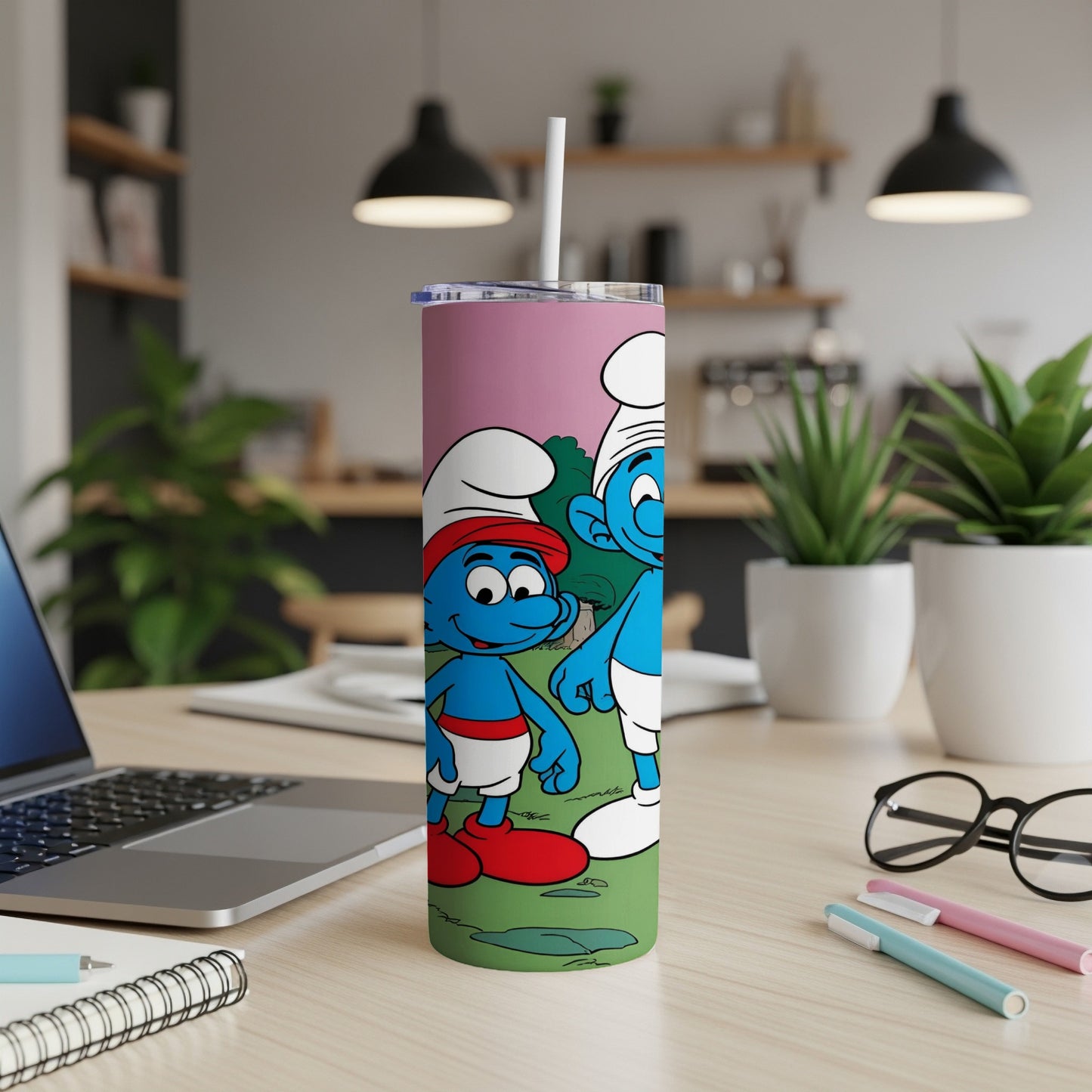 Smurfs in chef hats on a pink tumbler with a straw, on a desk.