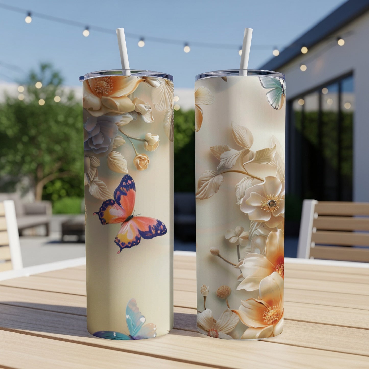 Two tall, insulated tumblers with butterfly and floral designs on a table.