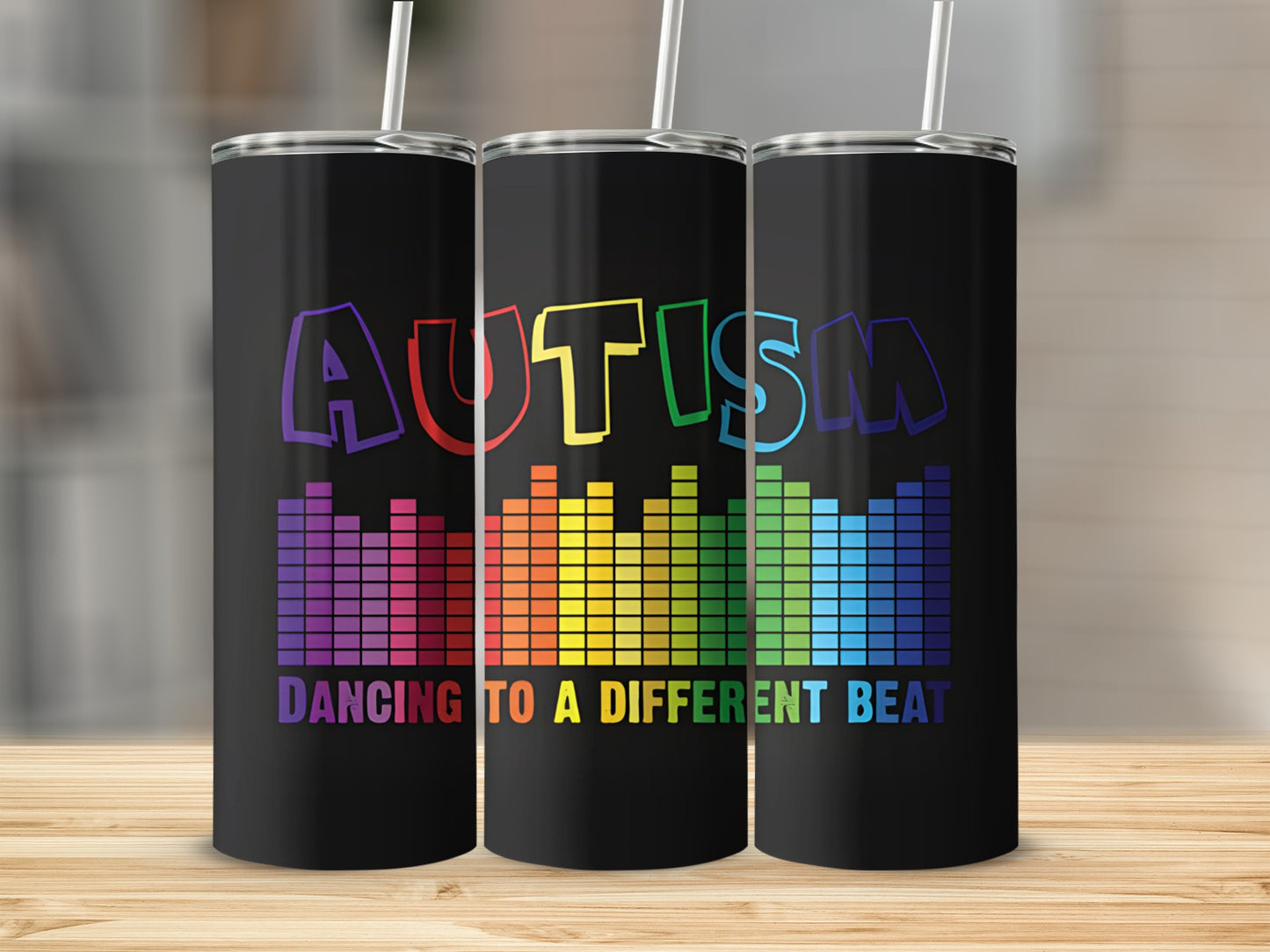 Black tumblers with "AUTISM" in rainbow colors and "DANCING TO A DIFFERENT BEAT" text.