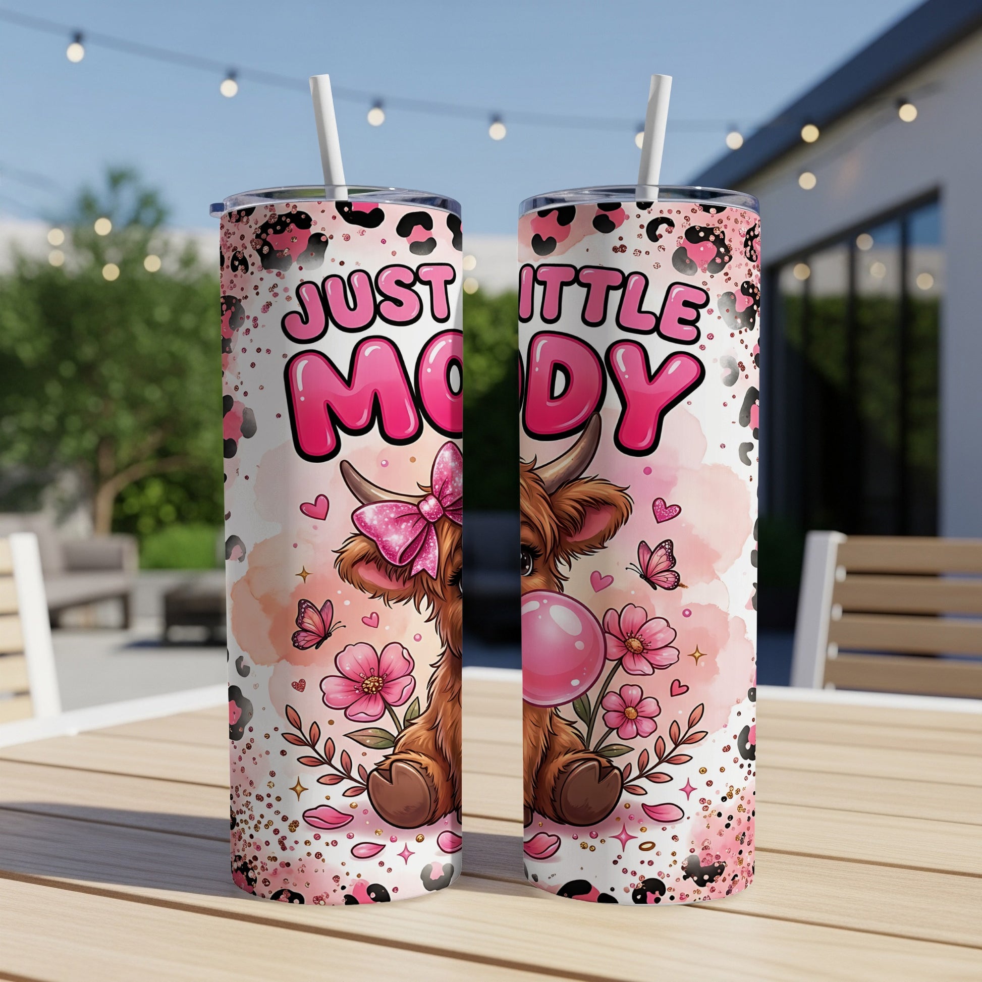 Pink tumbler with "Just a Little Moody" text and a cartoon cow with a bow.