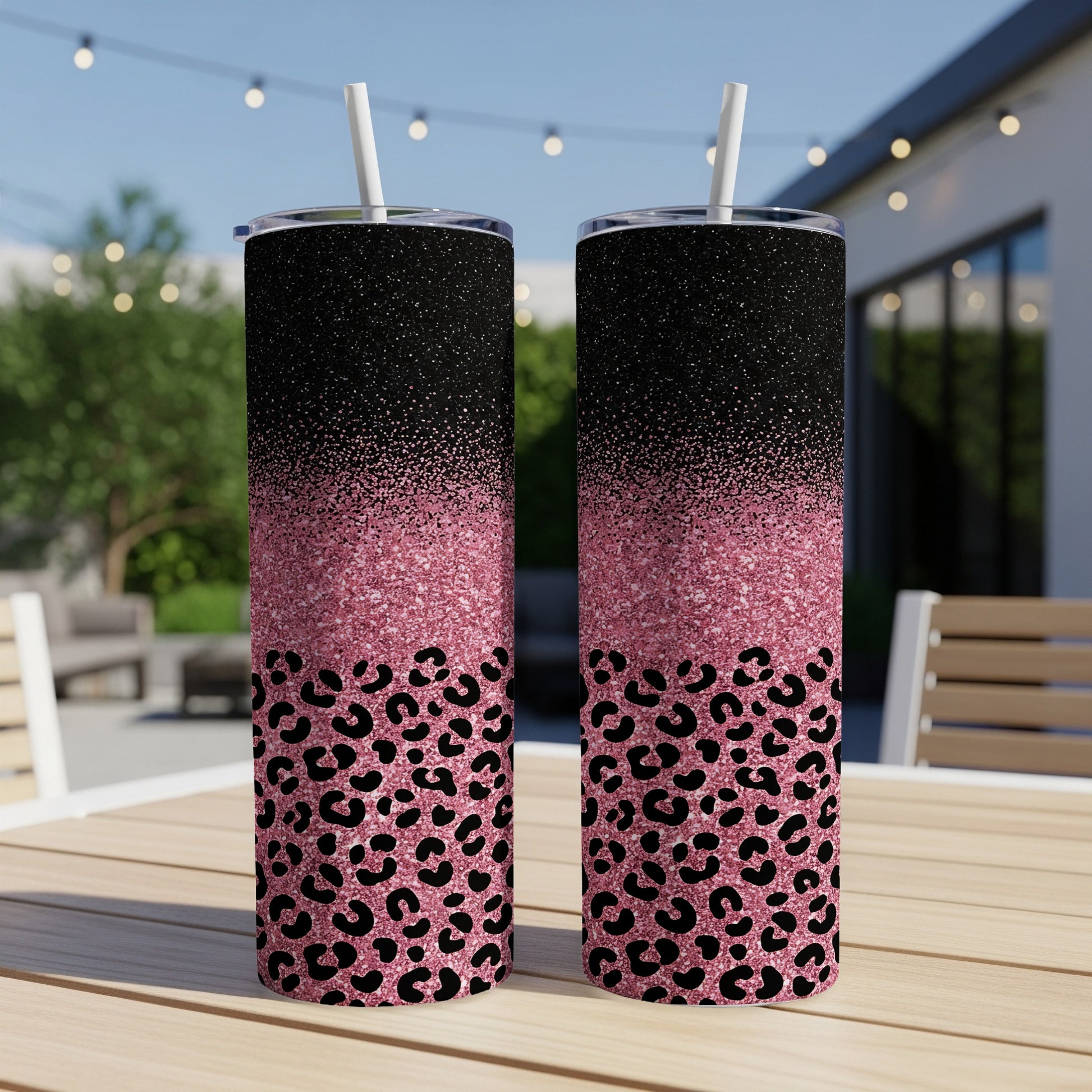 Two glittery tumblers with leopard print design on wooden table outdoors.