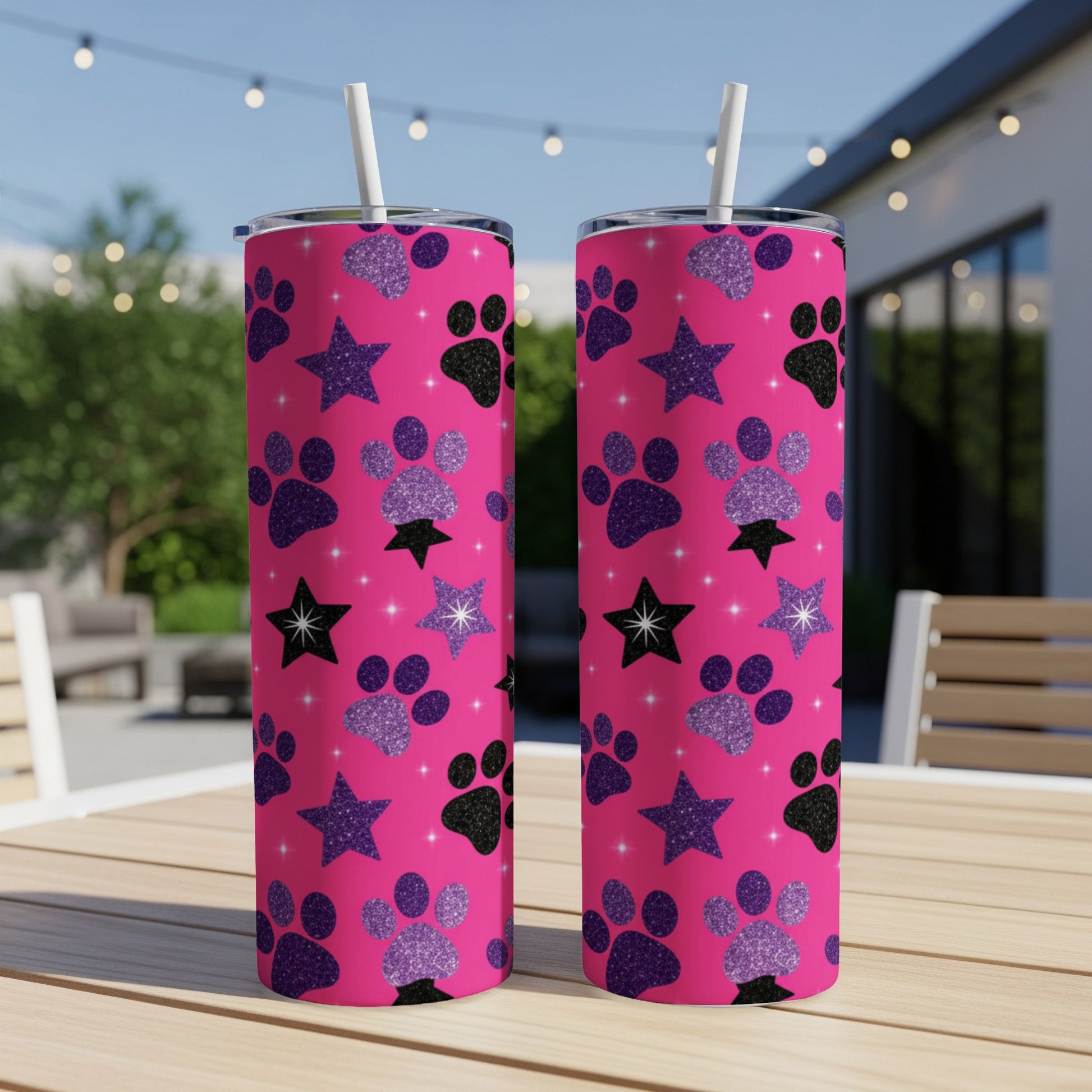 Two pink tumblers with paw print and star pattern, outdoors.