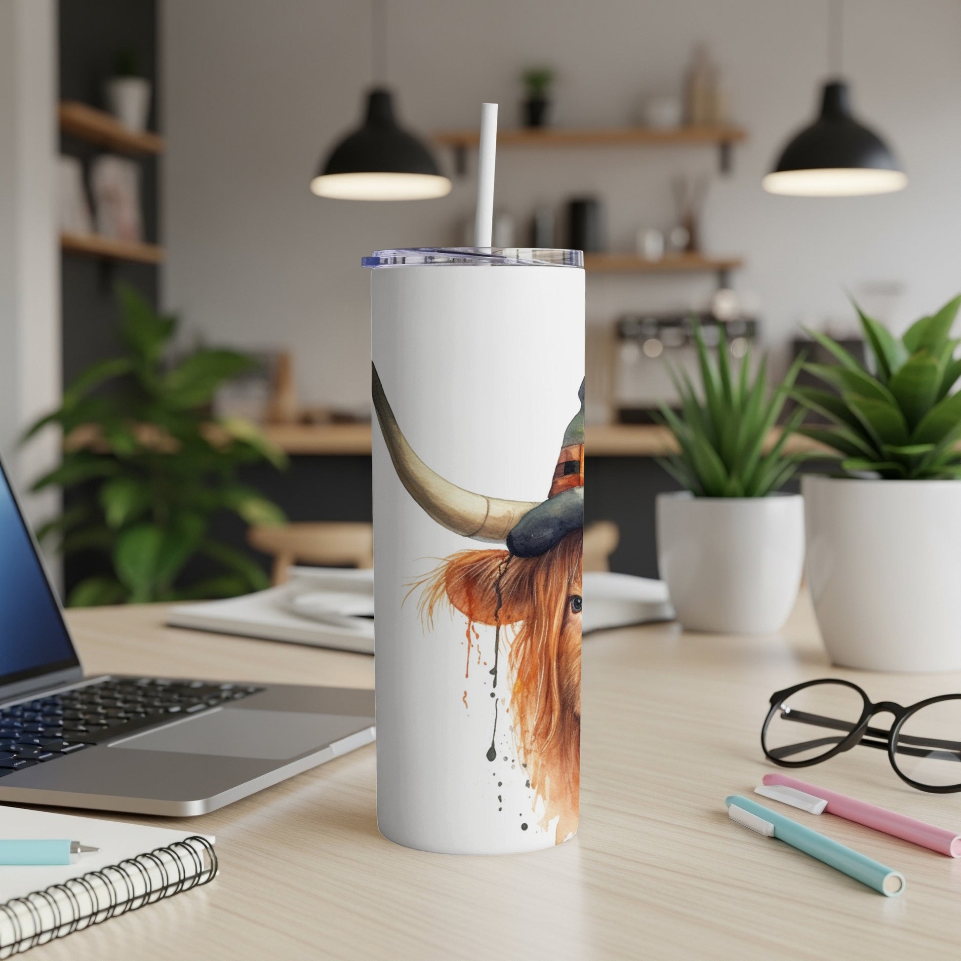 White tumbler with a watercolor painting of a Highland cow wearing a witch's hat.
