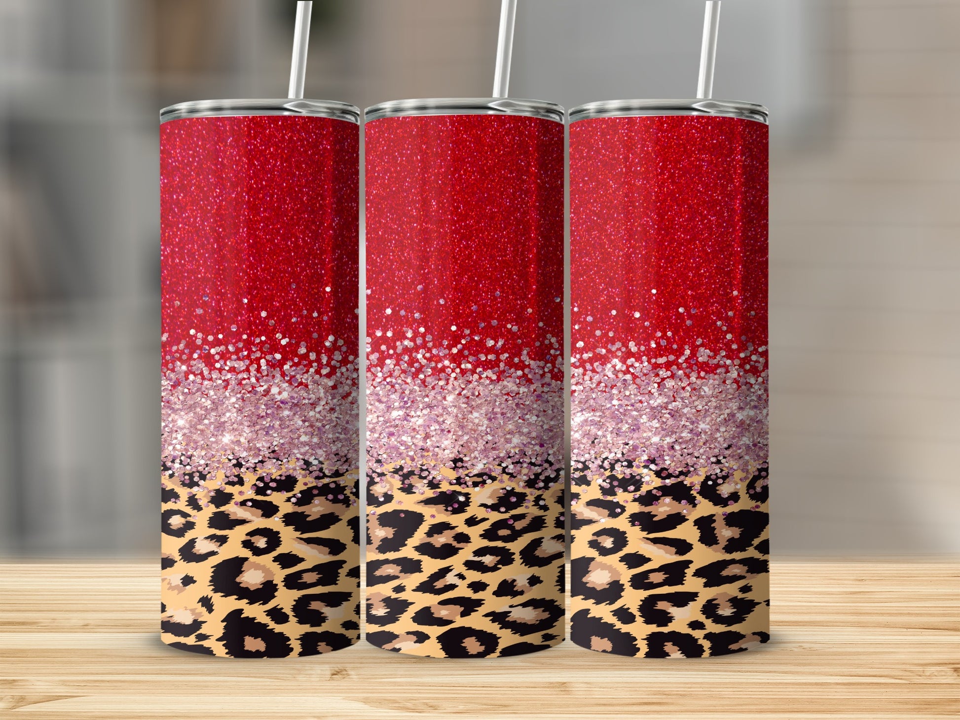 Three red glitter tumblers with leopard print design on a wooden surface.
