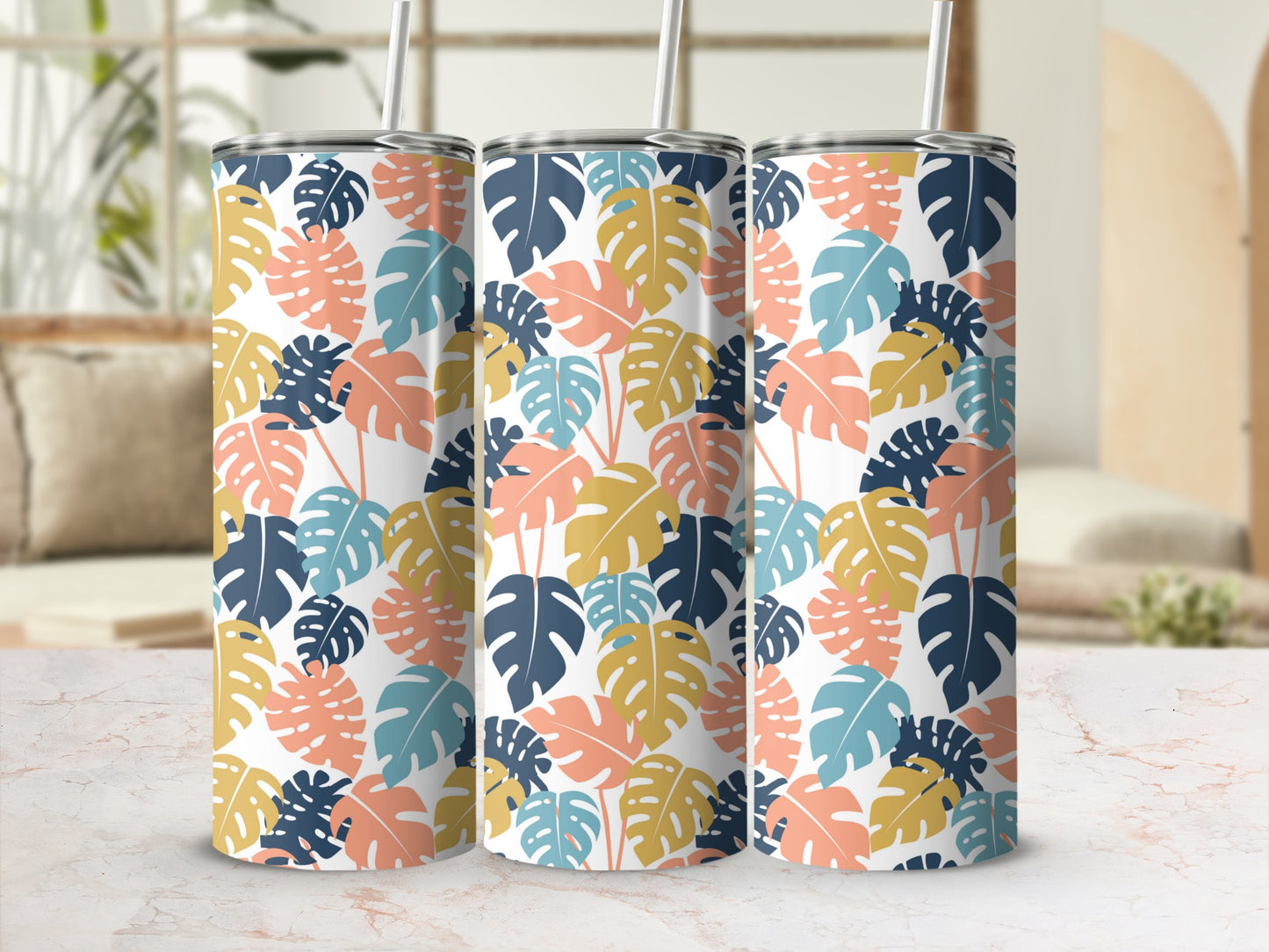 Three tumblers with a monstera leaf pattern in blue, orange, and cream.