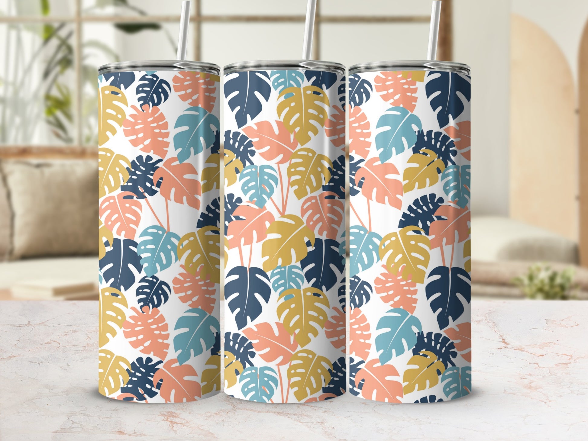 Three tumblers with a monstera leaf pattern in blue, orange, and cream.