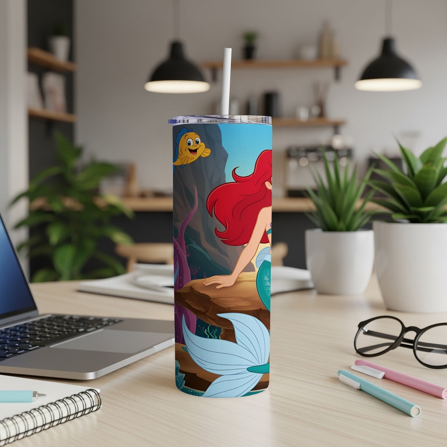 Ariel the mermaid and Flounder on a tumbler, sitting on a rock with a coral background.