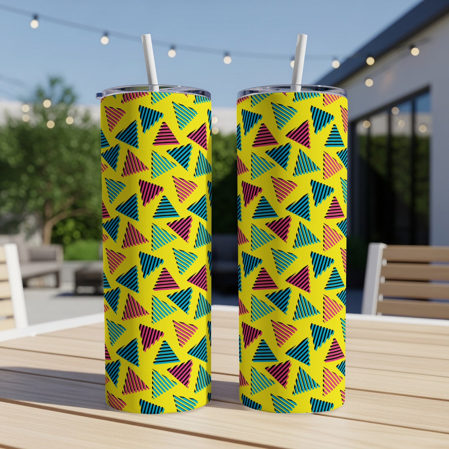 Two yellow tumblers with a retro geometric triangle pattern and white straws outdoors.