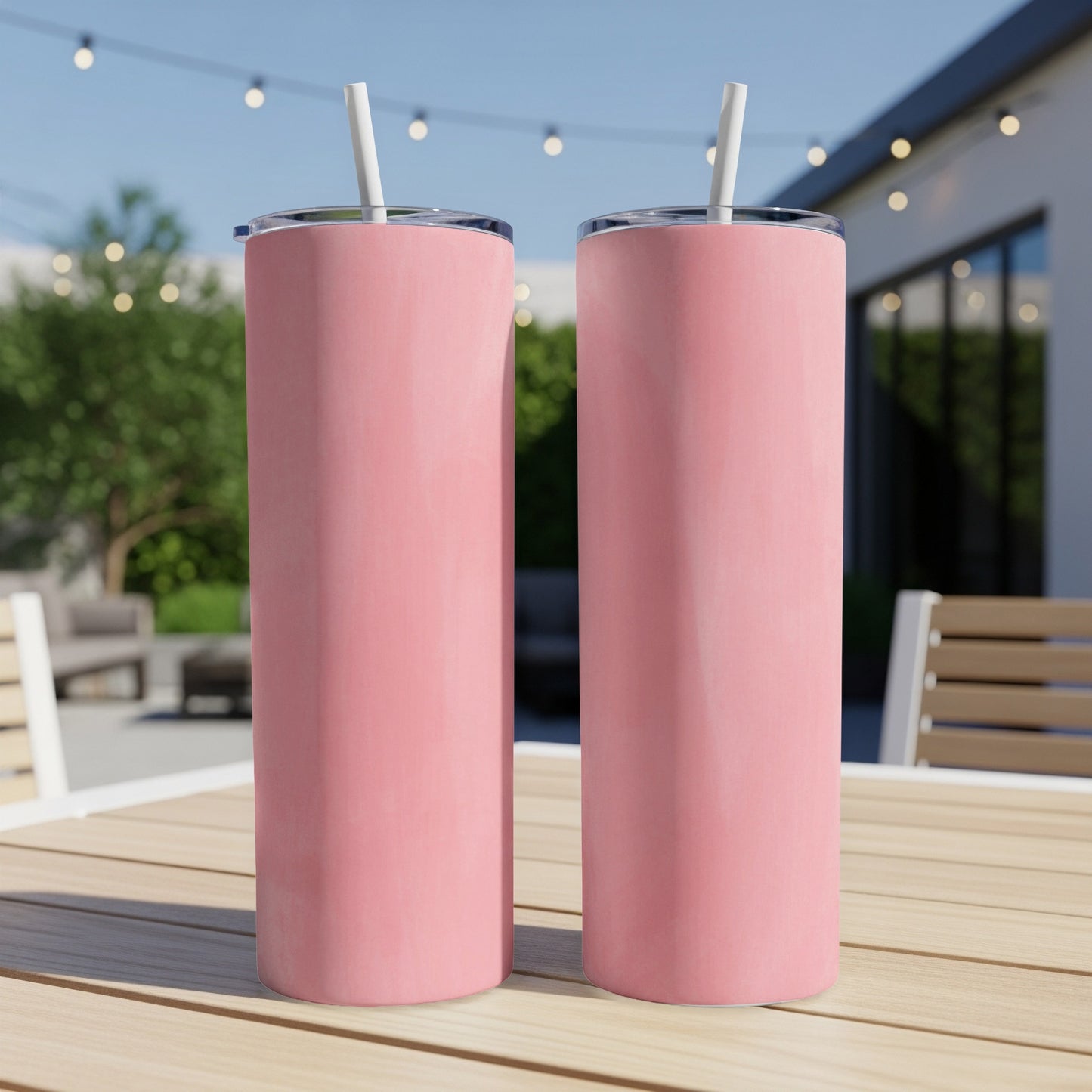 Two pink tumblers with straws on a wooden table.