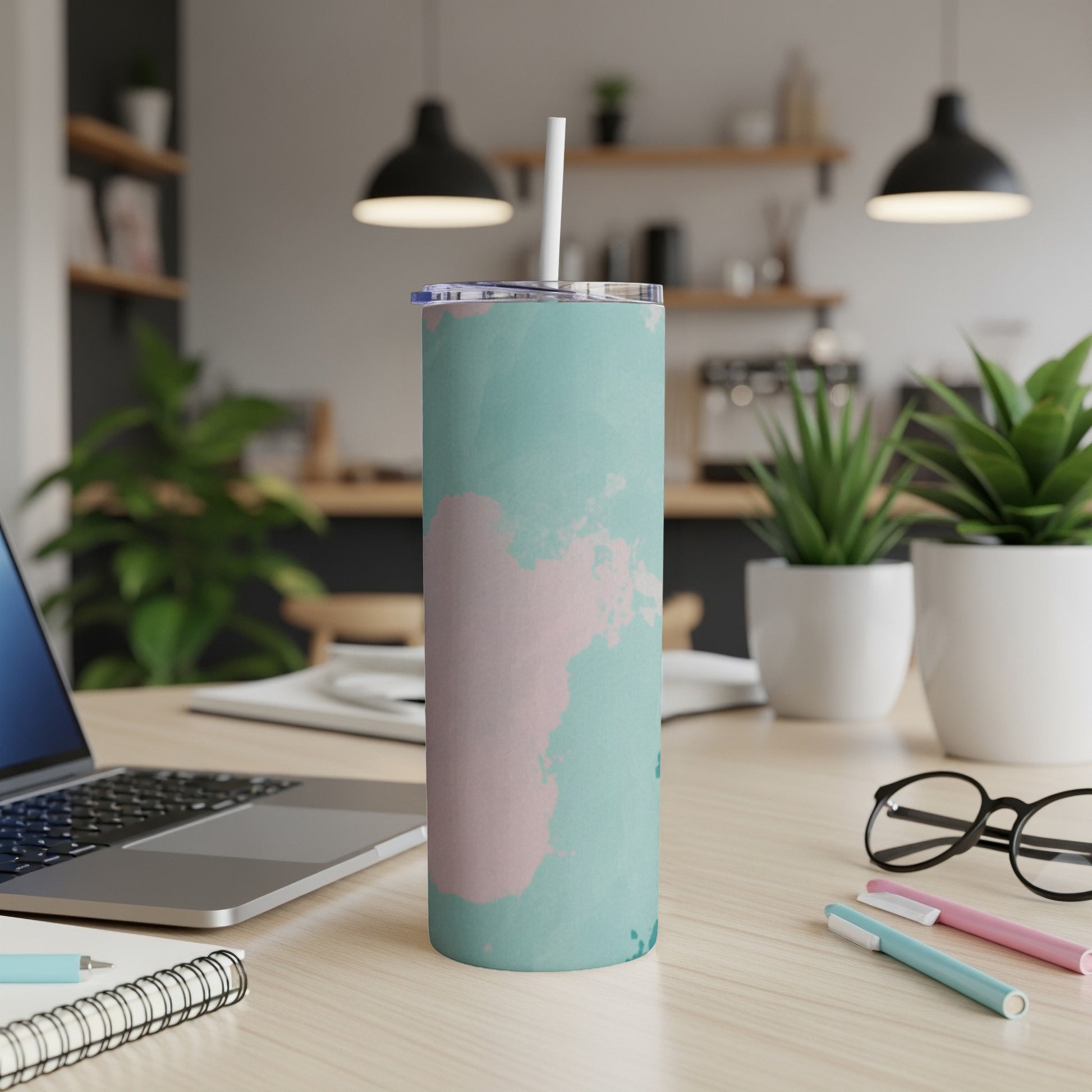 Teal and pink marbled tumbler with straw on a desk.