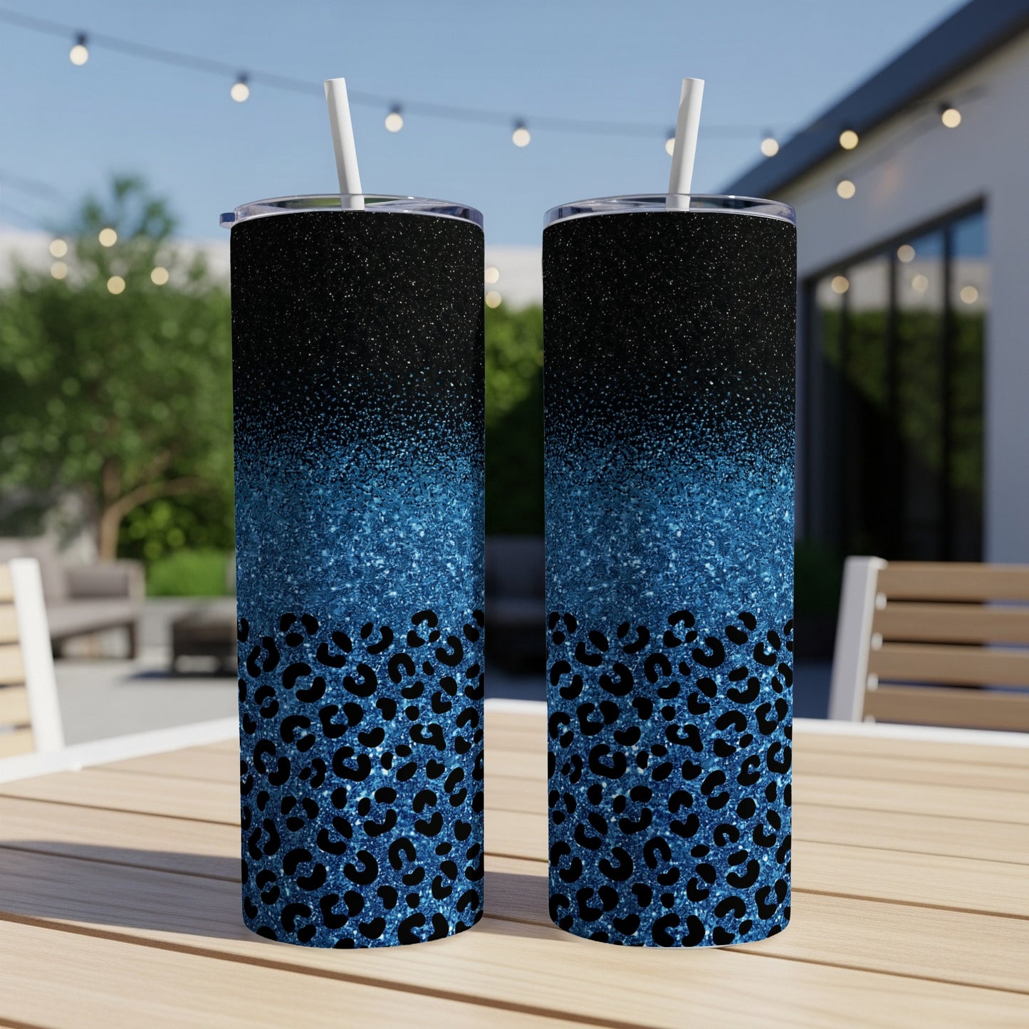 Two blue glitter and leopard print tumblers with straws on a table.