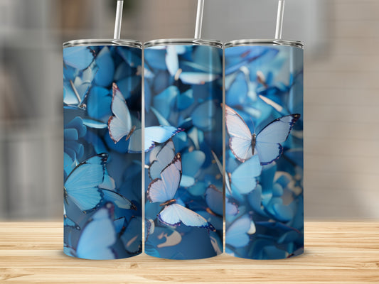 Three blue butterfly tumblers with straws on a wooden surface.