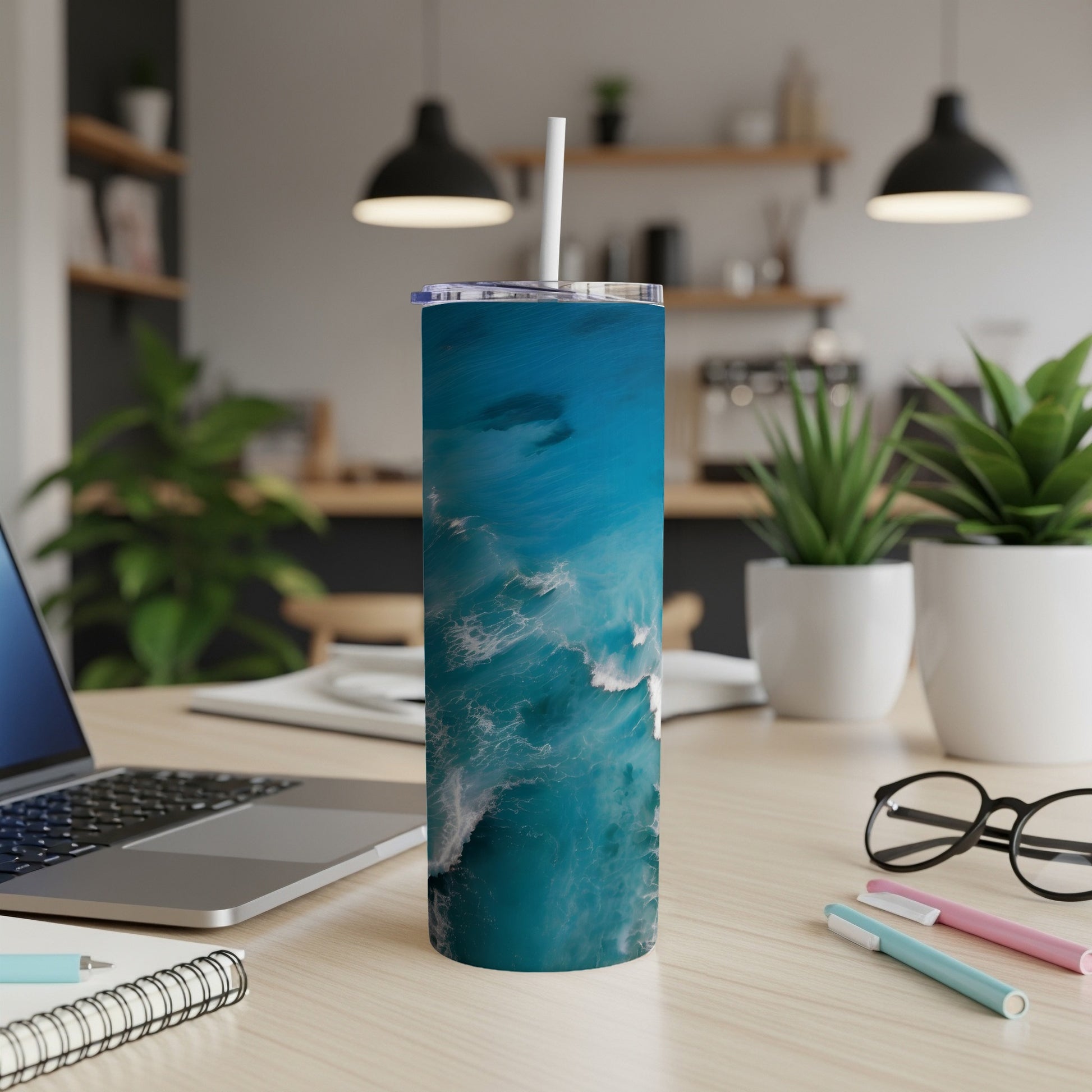 Blue ocean wave pattern on a white tumbler with a straw on a desk.