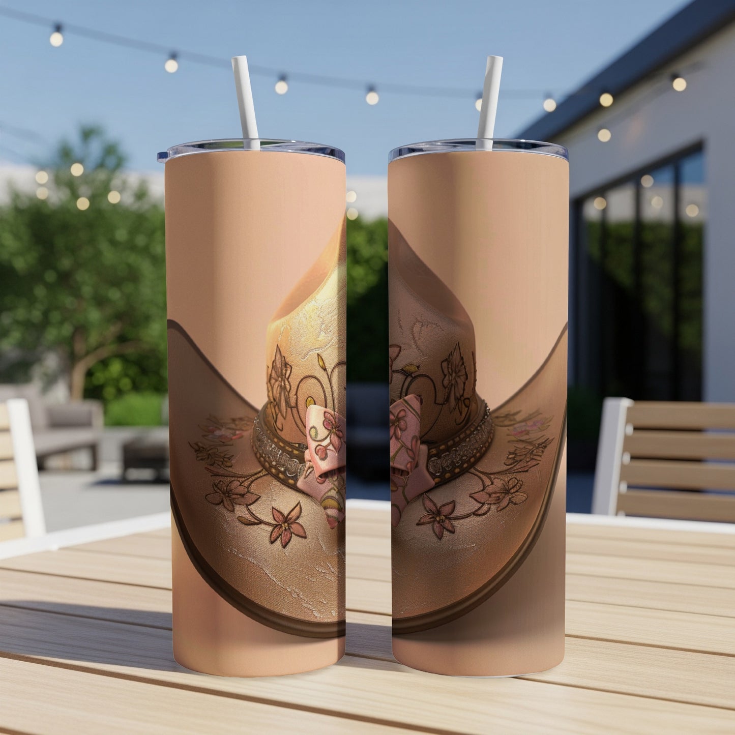 Two tumblers with floral cowboy hat design sit on a patio table.