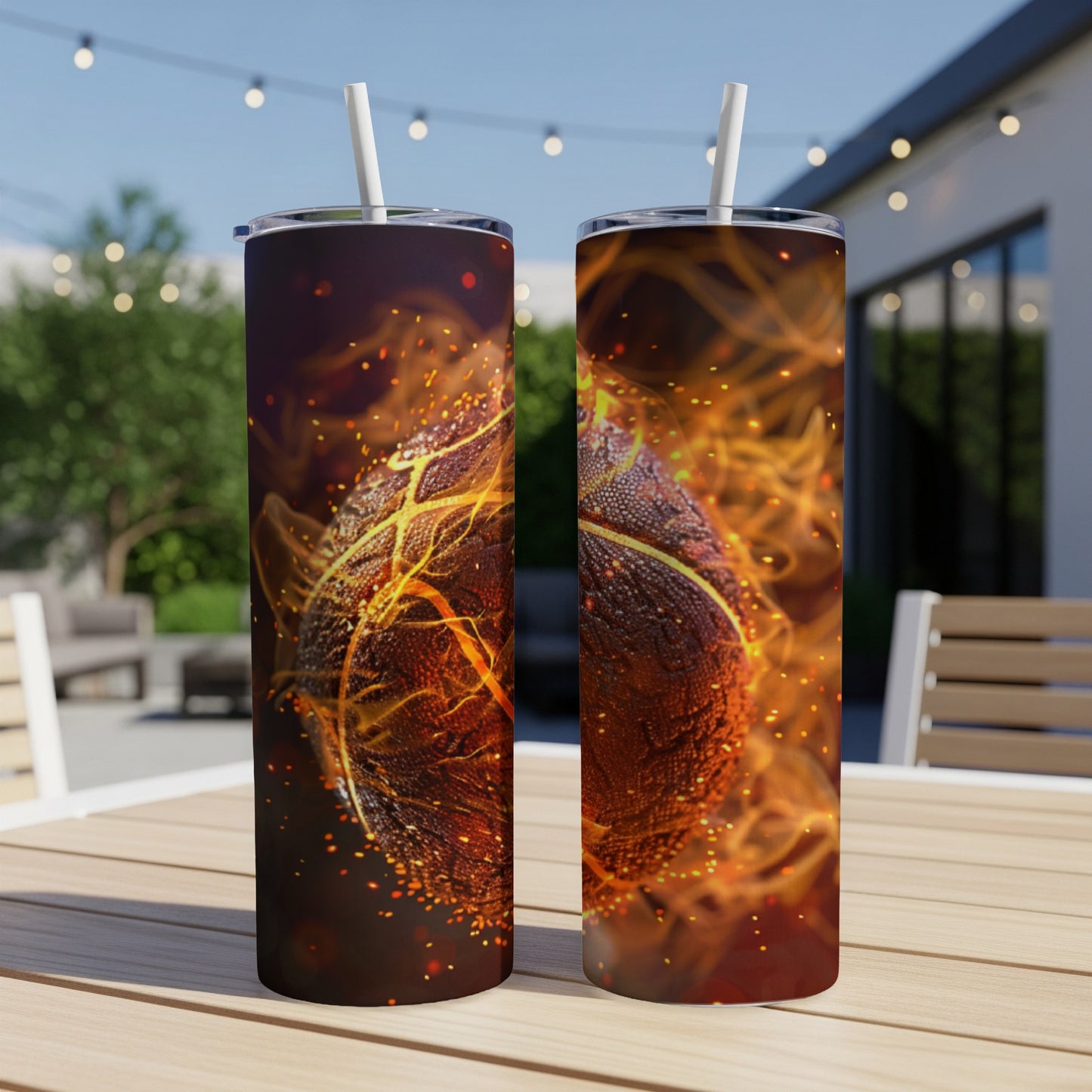 Two basketball-themed tumblers with fiery designs, set on a patio table.