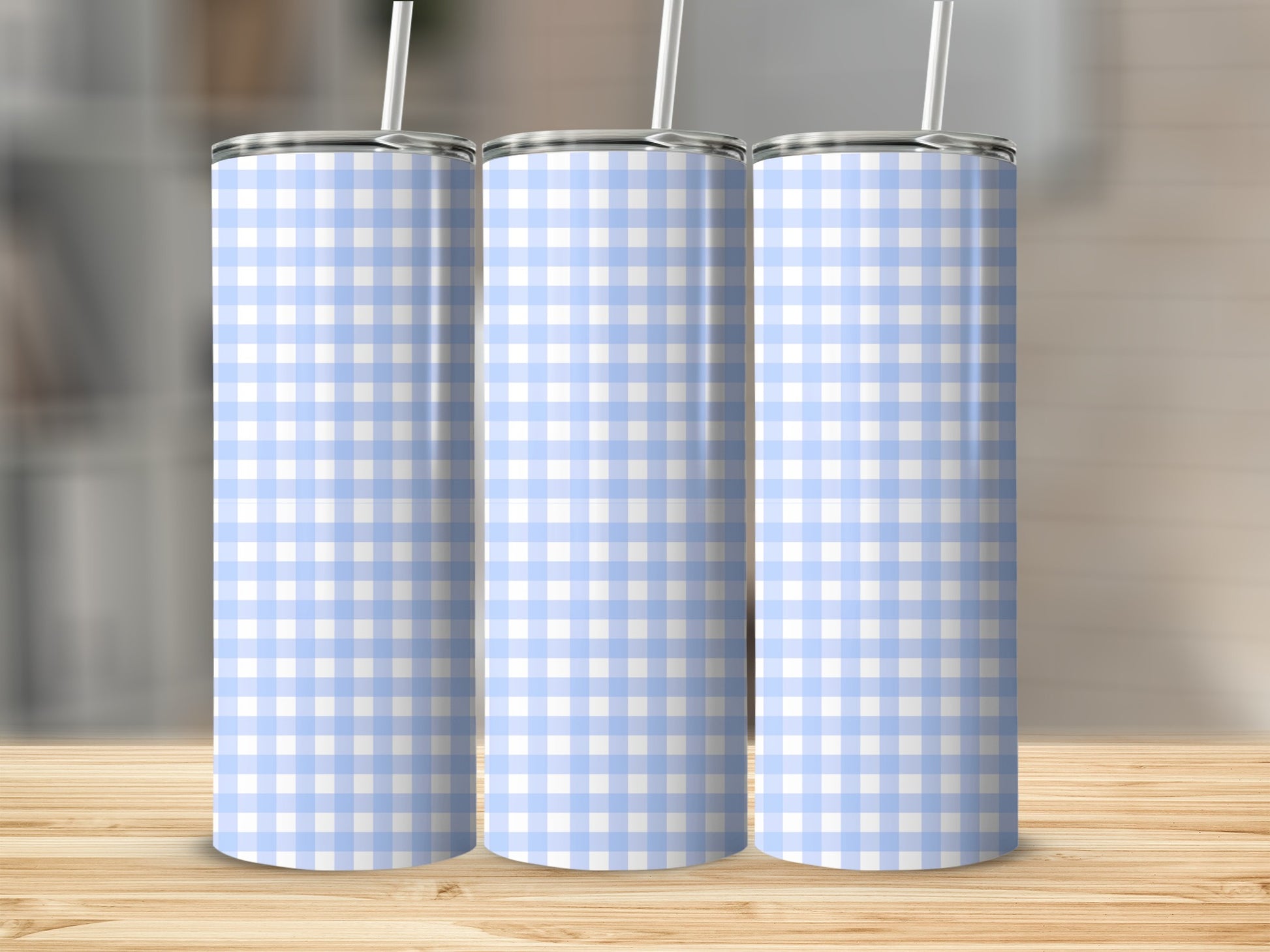 Three blue and white checkered tumblers with straws on a wooden surface.