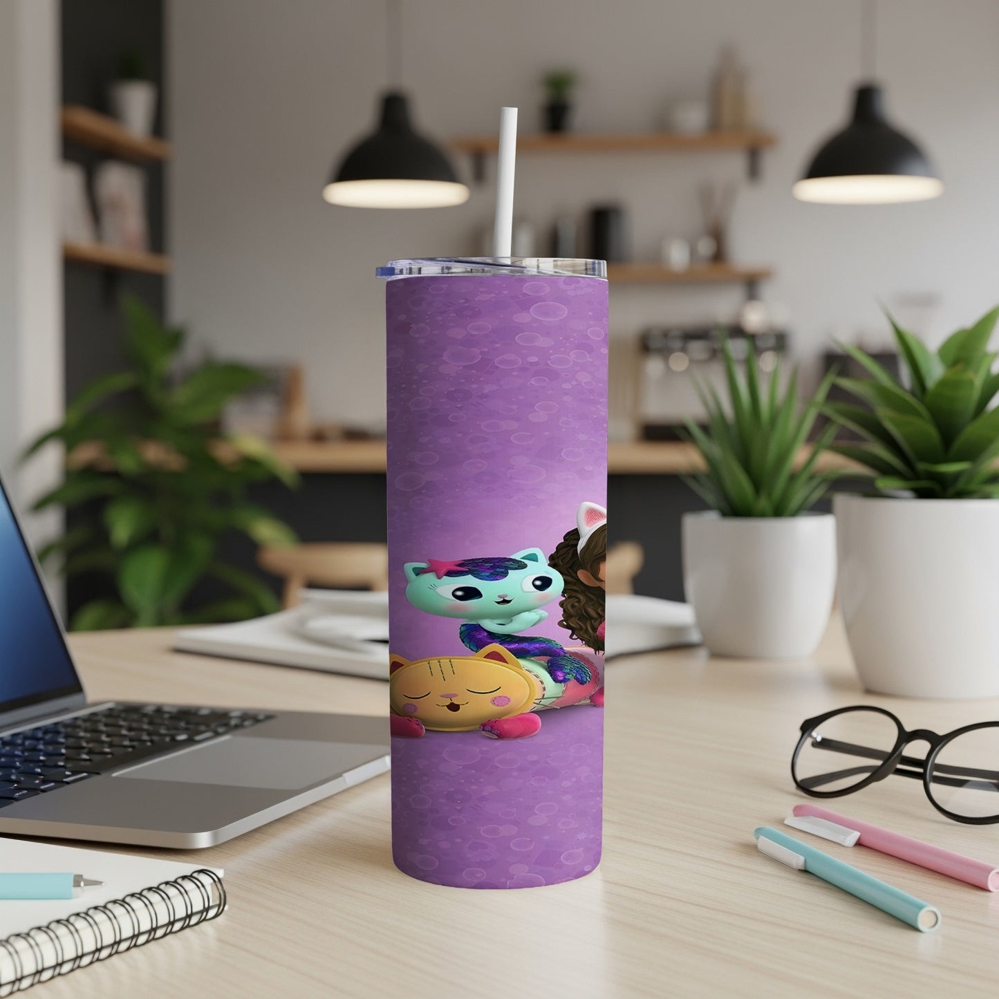 Purple tumbler with colorful cartoon cats, sitting on a desk.