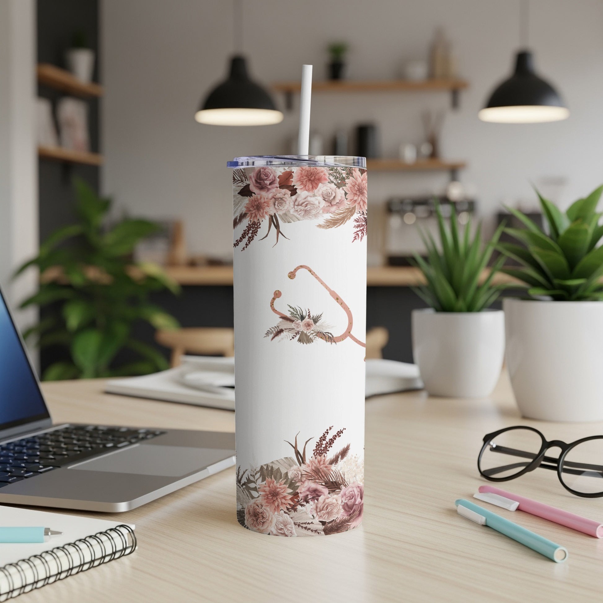 White tumbler with floral pattern and stethoscope, straw inserted.