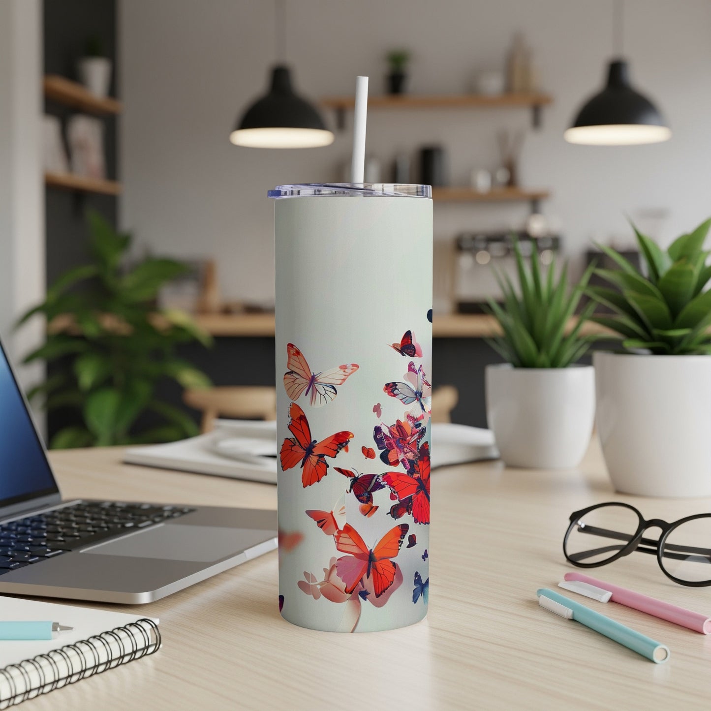 White tumbler with red and orange butterfly design on desk.