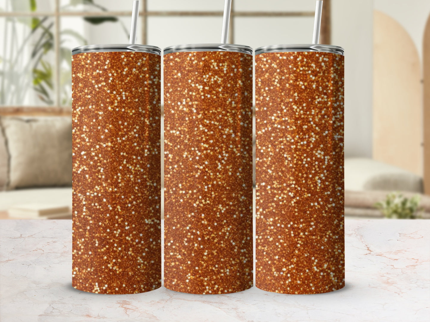 Three glitter-covered tumblers with straws on a marble surface.