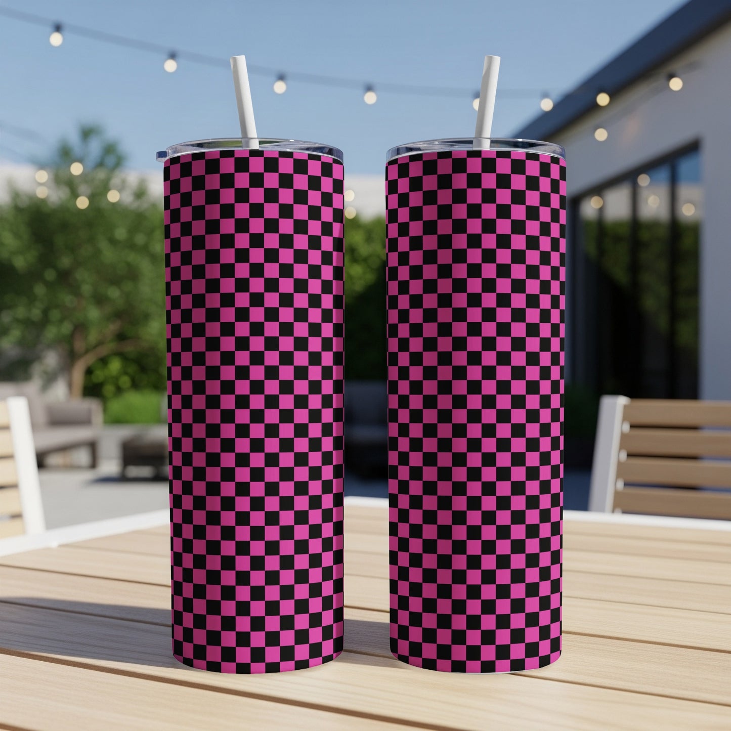 Two pink and black checkered tumblers with straws on a wooden table.