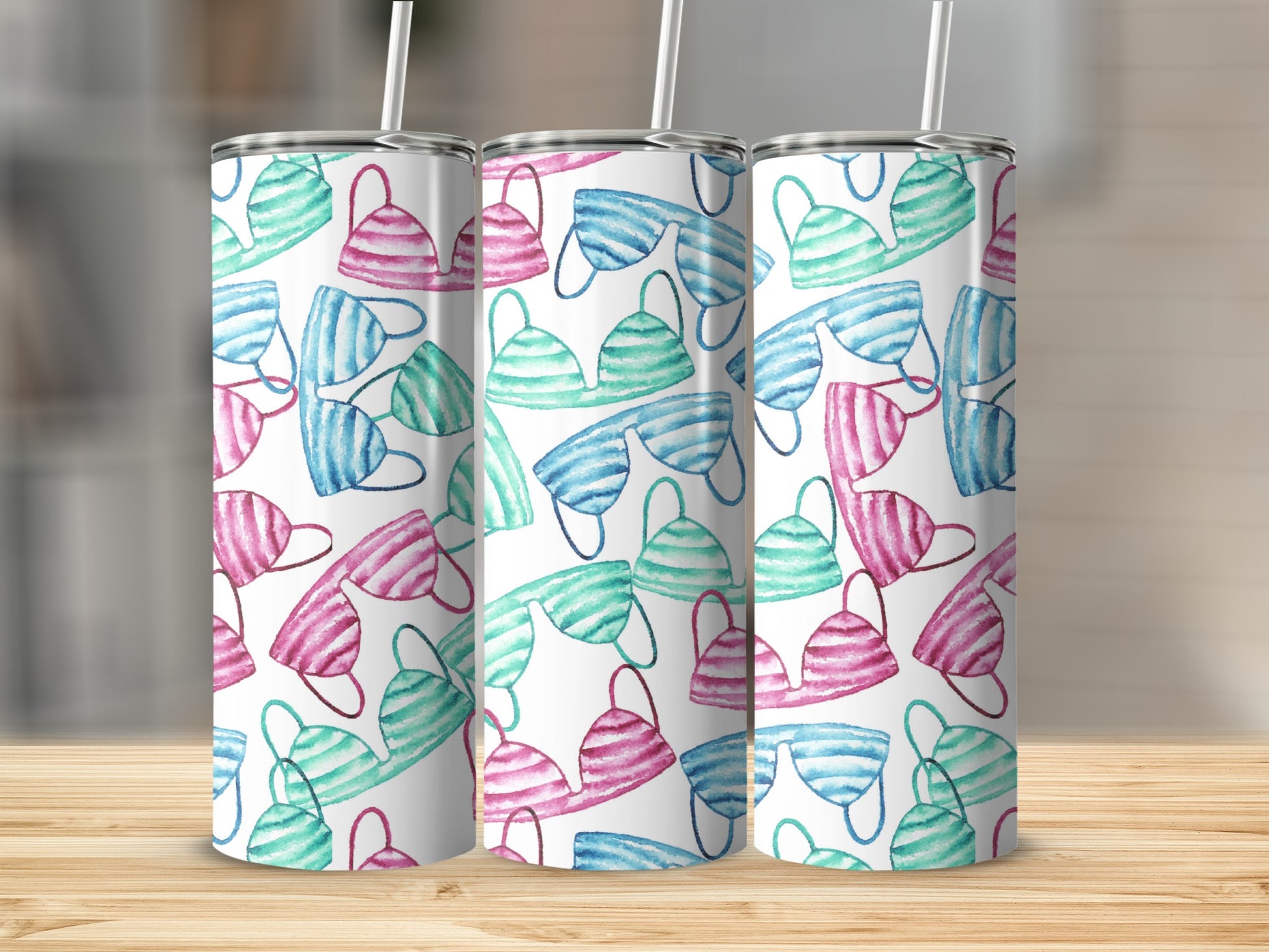 Three skinny tumblers with a watercolor pattern of pink and teal bikinis.