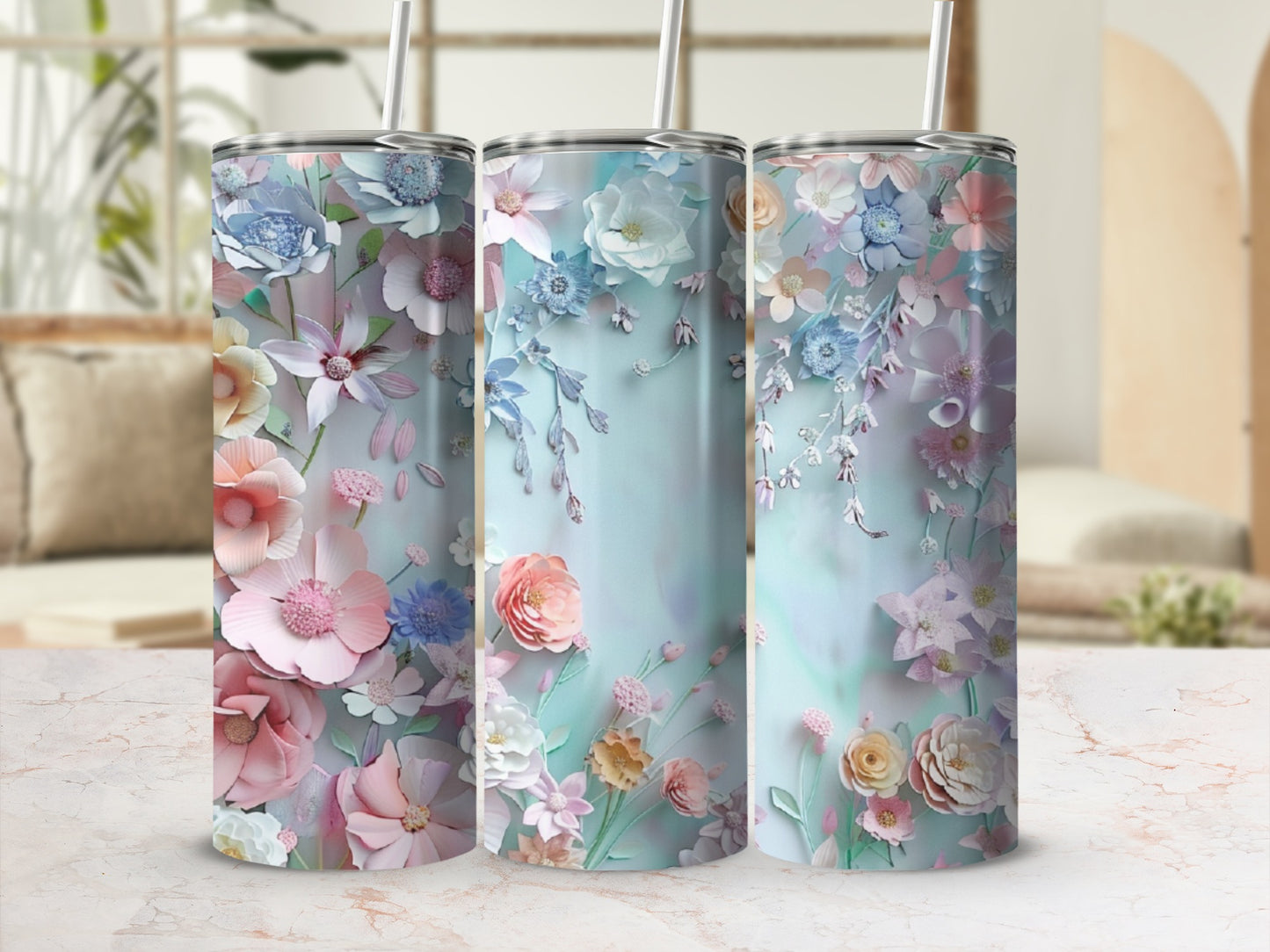 Three floral tumblers with pastel flowers and leaves on a marbled surface.