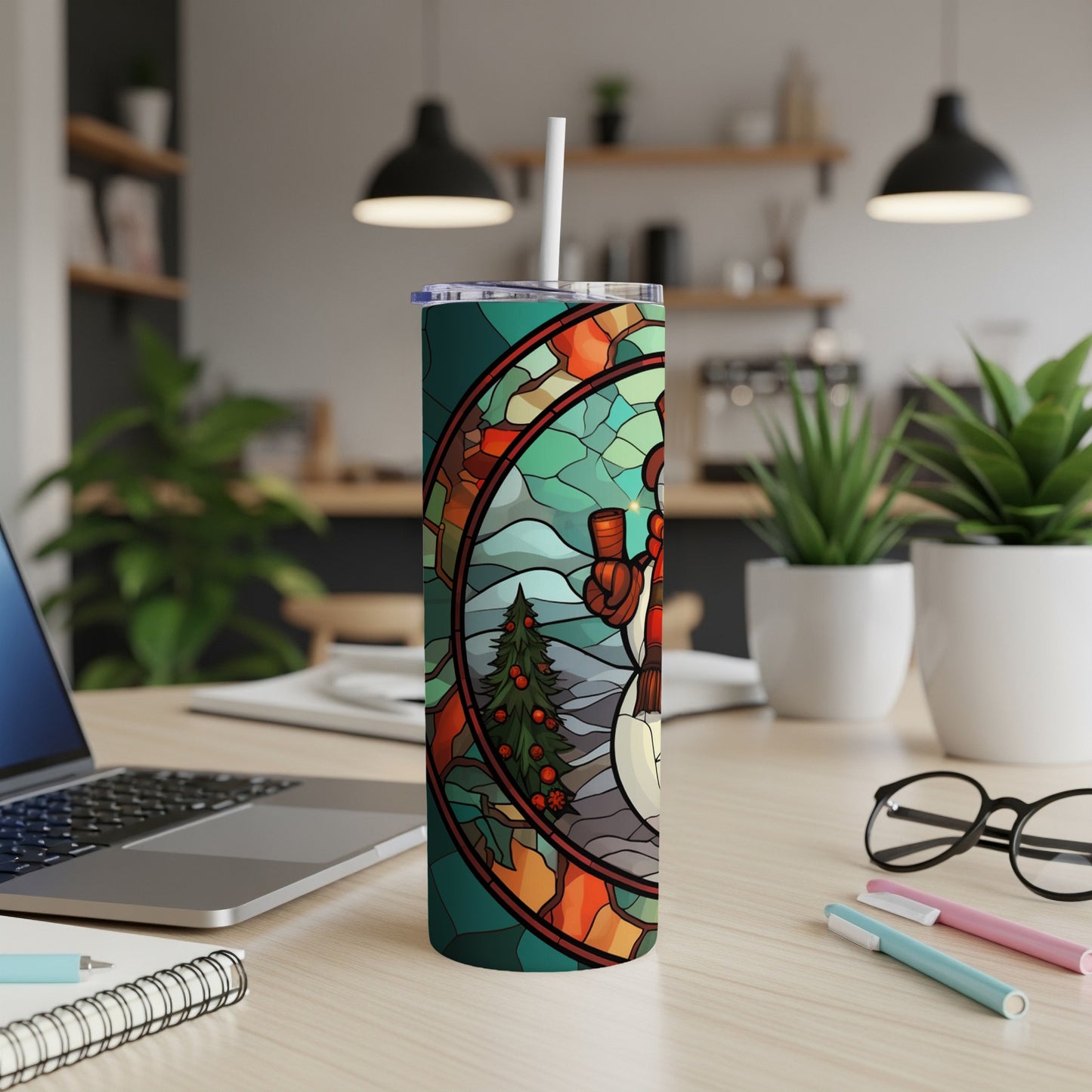 Stained glass snowman and Christmas tree tumbler with straw on desk.