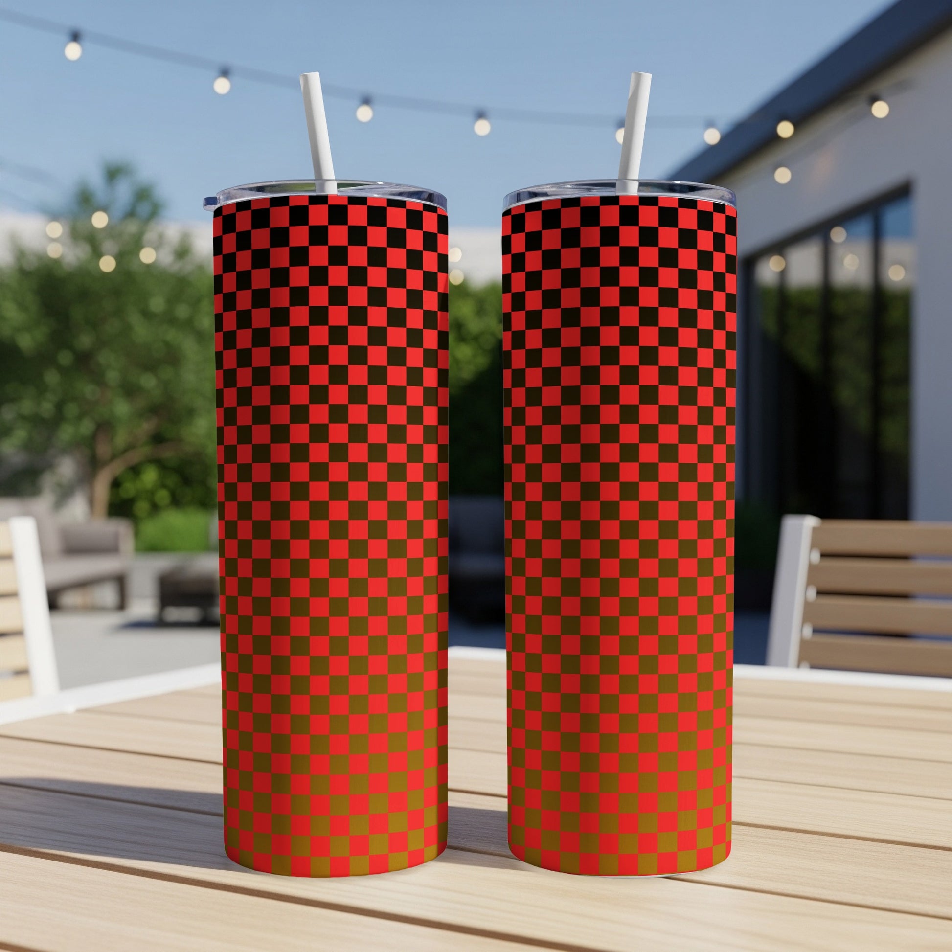 Two red and black checkered tumblers with straws on a table.