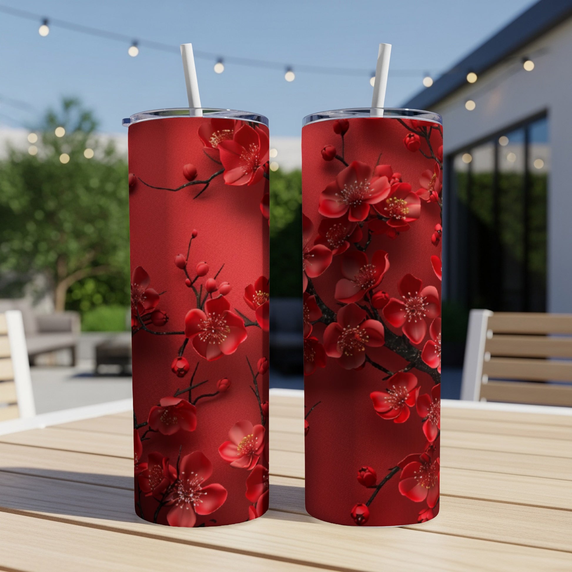 Two red tumblers with blooming cherry blossoms and white straws.