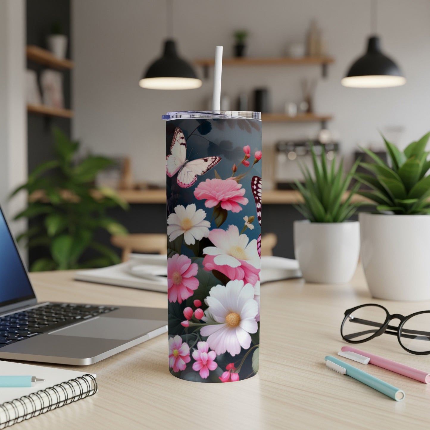 Floral tumbler with butterflies and a straw on a desk.