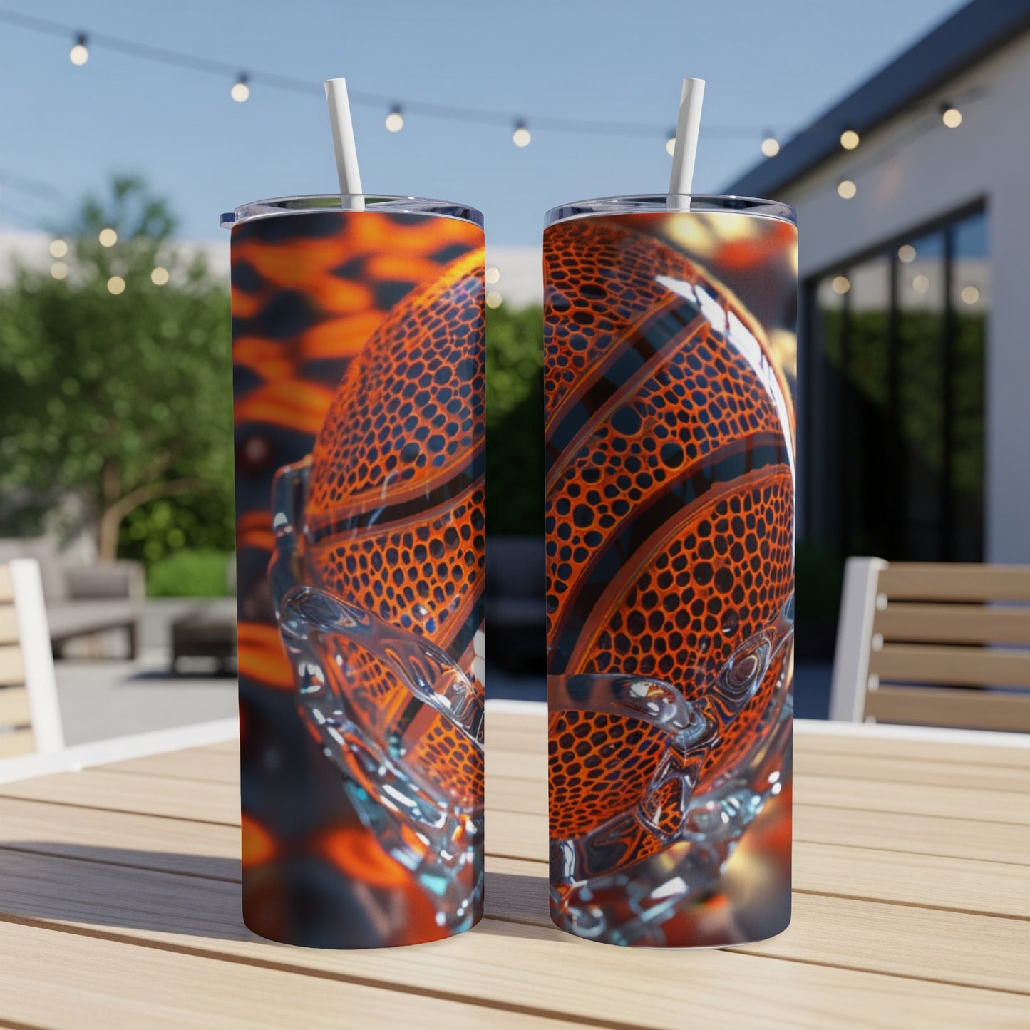 Two stainless steel tumblers featuring a basketball design on a wooden table outdoors.