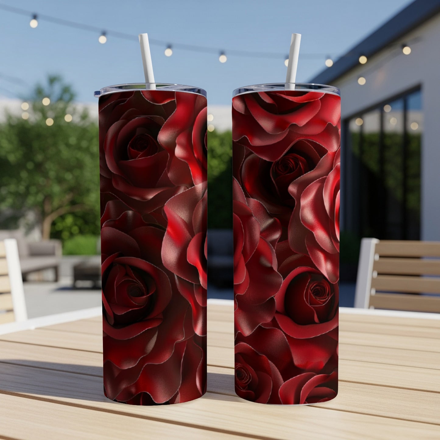 Two tumblers with deep red rose pattern on outdoor table.