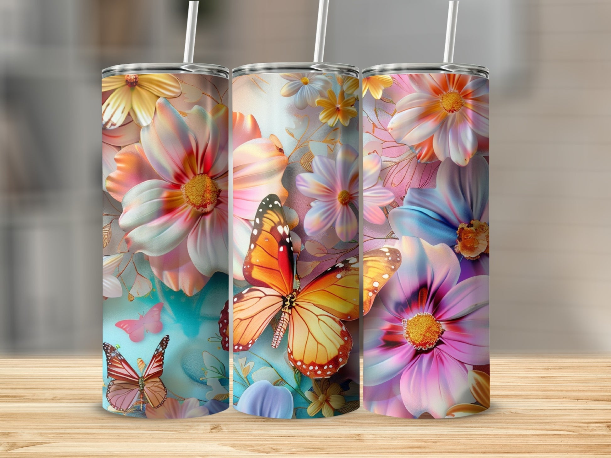 Three tumblers with colorful floral and butterfly designs on a wooden surface.
