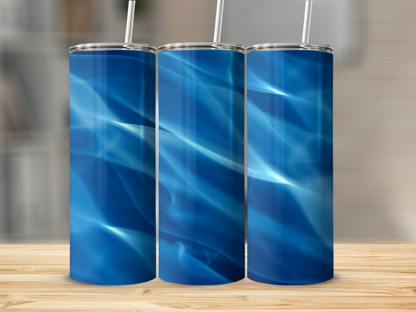 Three blue tumblers with abstract water-like patterns and straws.