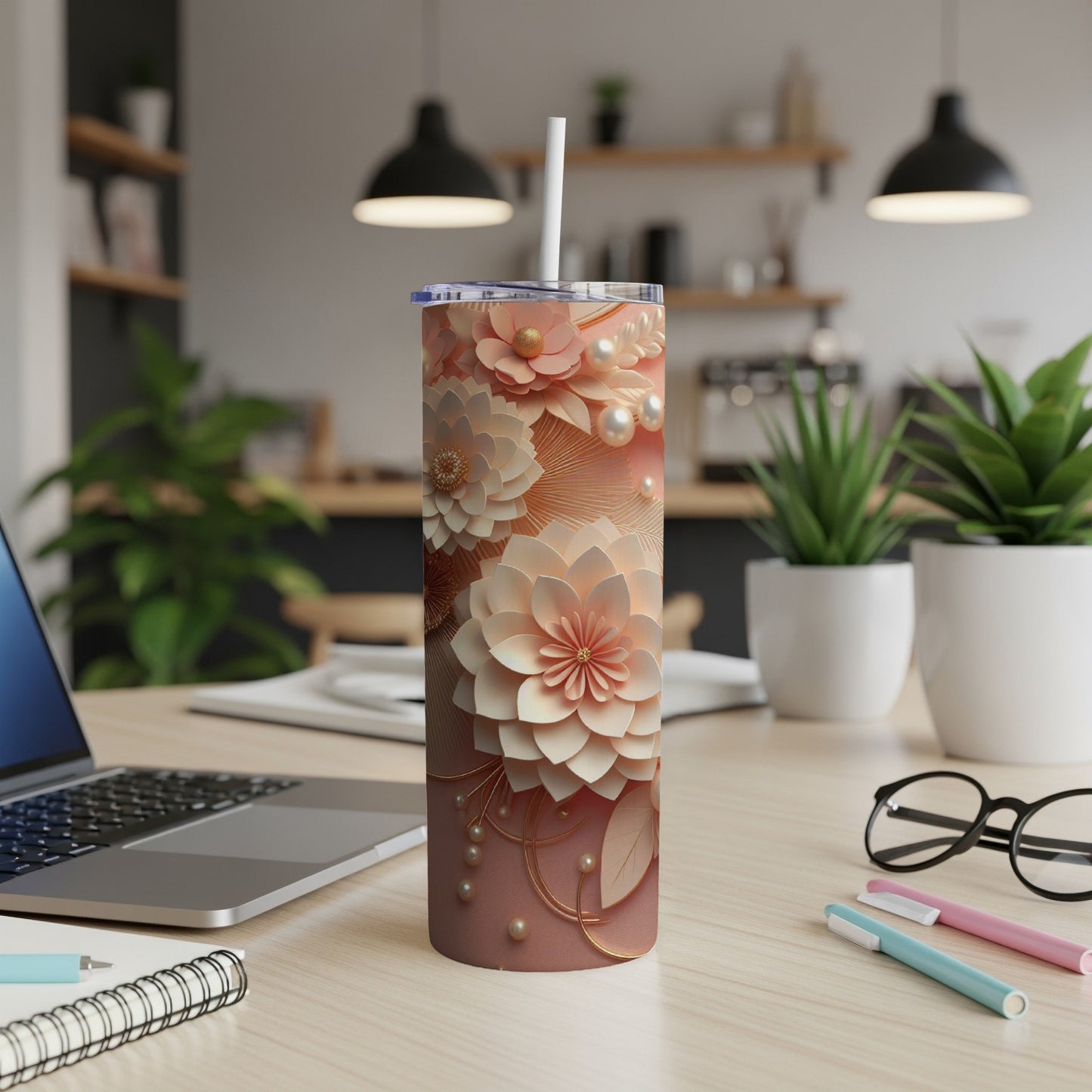 Pink floral tumbler with pearls and leaves on a wooden desk with laptop.
